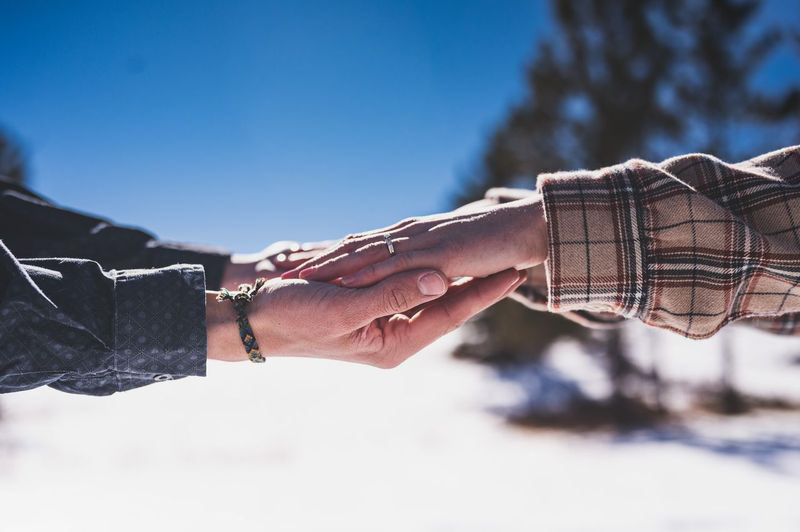 Color CCPLLC Cheyenne WY Intimate Portrait of an engaged couple holding hands outside in the snow wearing long sleeves
