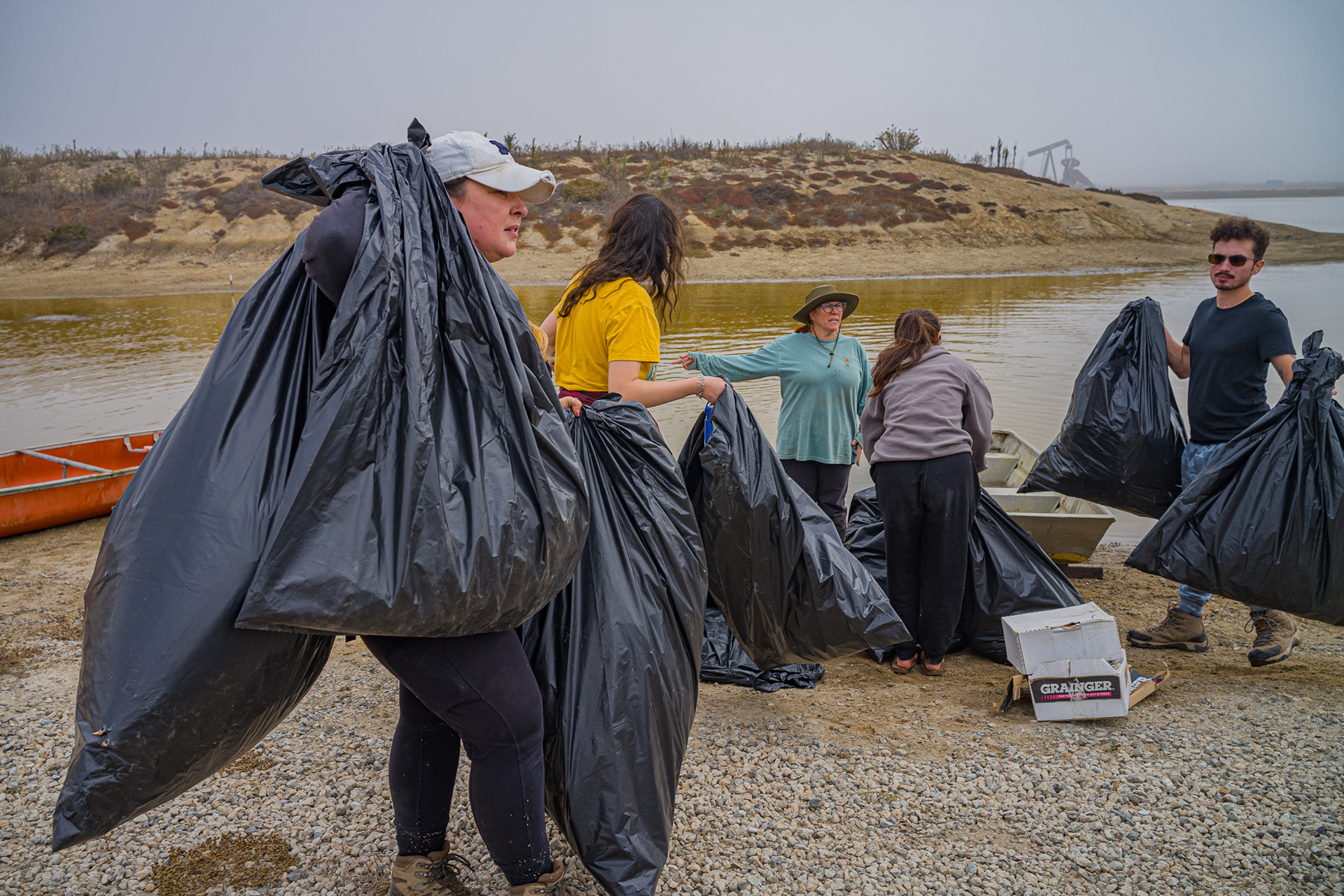 Katy Leach who serves on the Board of Directors at Bolsa Chica Land Trust carries bags of plants that were removed from the island. It is put in an area where it can decompose.  Photo Credit: Justin Enriquez