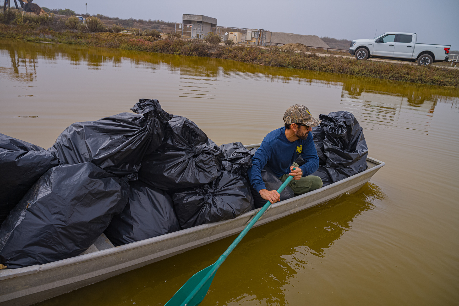  Fish and Wildlife Technician Vincent Charles carries all the bag of plants that were removed from the island and put on the other side of the river. The bags of plants would be dumped in an area where they can be decomposed.  Photo Credit: Justin Enriquez