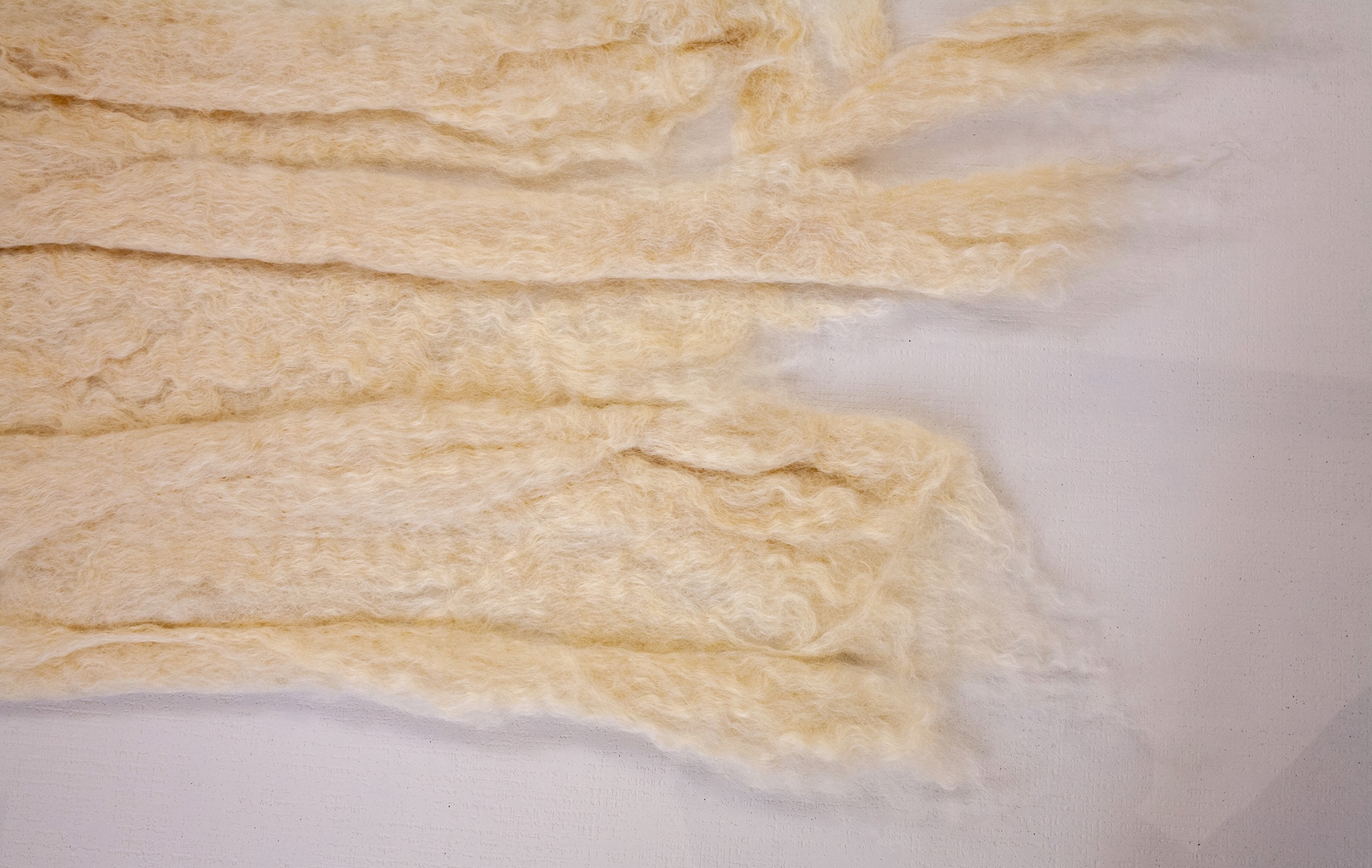 Detail of The Unfolding showing layered pale felted wool bands with wispy edges on clear polycarbonate.
