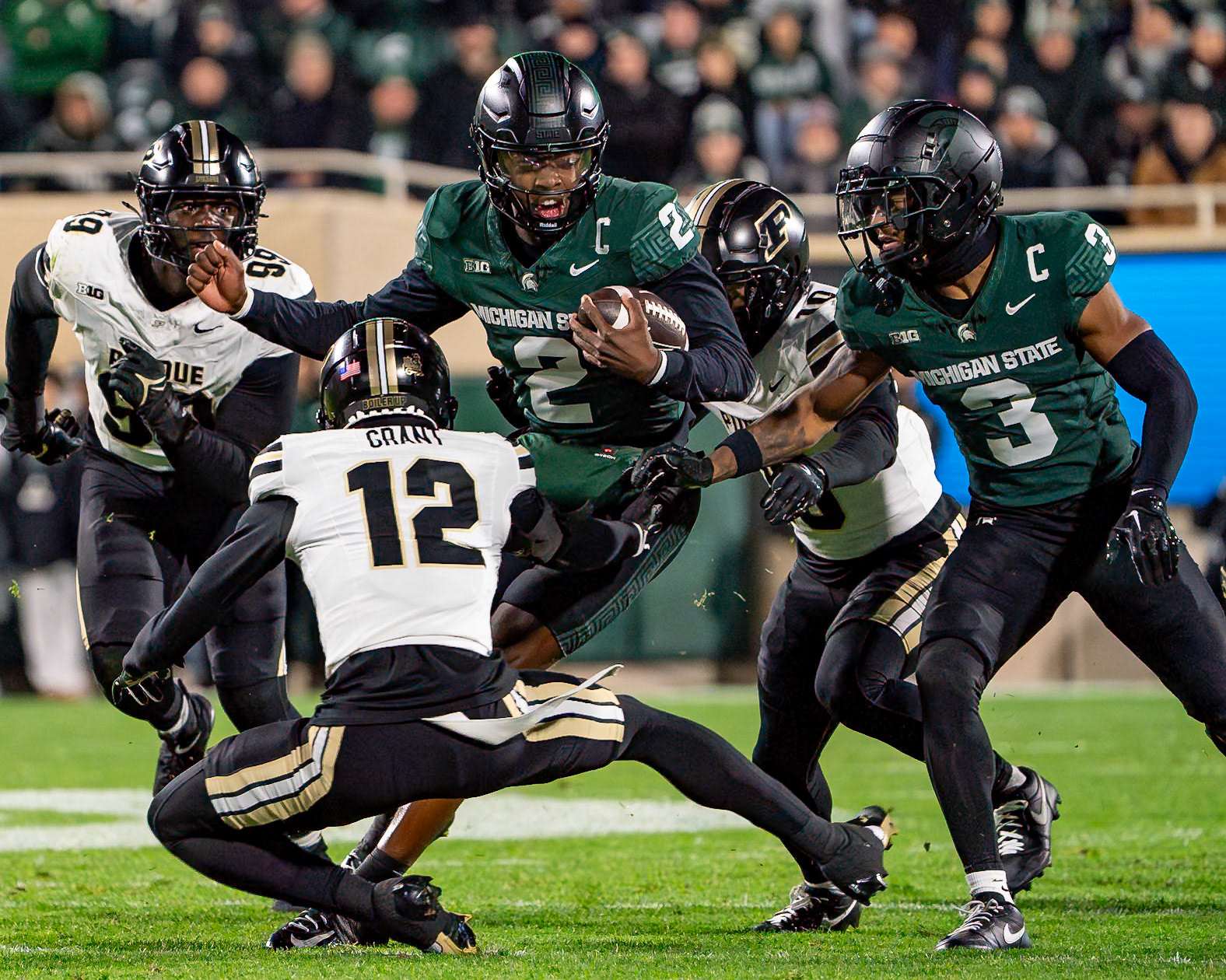 EAST LANSING, MI - NOVEMBER 22, 2024: Michigan State University Quaterback Aidan Chiles (2) trying to evade Purdue University's Freshman Defensive Back Tarrion Grant (12), during the Purdue University Boilermakers at Michigan State University Spartans Football game at Spartan Stadium(Photo by Steve Bowen / Bowen Arrow Photography / Northern Indiana Sports Report)