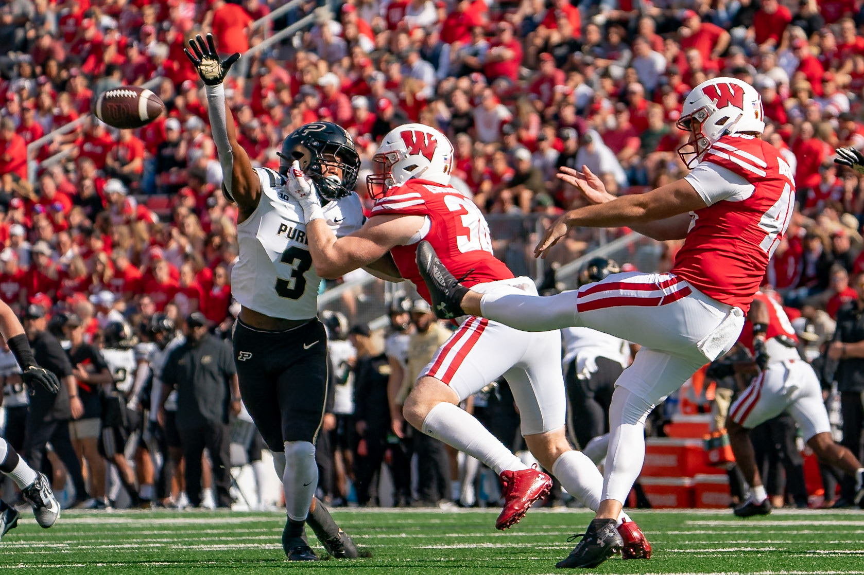 MADISON, WI - OCTOBER 5, 2024: University of Wisconsin Sophomore Punter Atticus Bertrams (49) kicking the ball while Purdue University Sophomore Defensive Back Derrick Rogers Jr. (3) tries to block it while be defended by University of Wisconsin Sophomore TE Tucker Ashcraft (38) during the Purdue University Boilermakers at University of Wisconsin Badger Football game at Camp Randall Stadium(Photo by Steve Bowen / NISports Report)