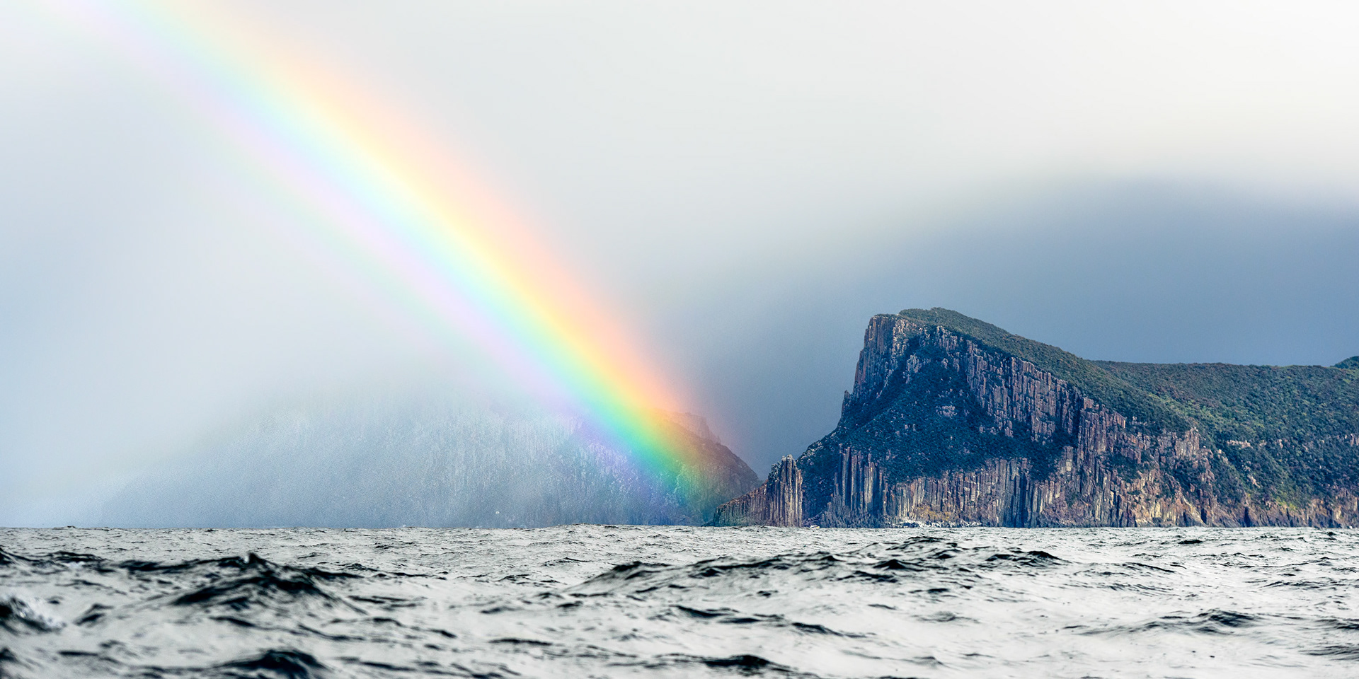 Rainbow Island / I took this shot from a small boat on a fishing trip off the coast of the Tasman Peninsula, Tasmania, Australia. Tasman Island is hidden in the mist behind the rainbow