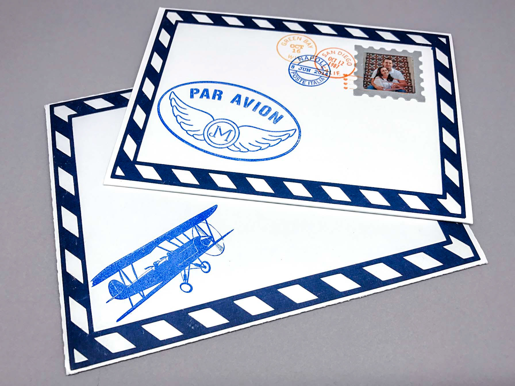 The bride requested an airmail theme, as the couple were being deployed to Italy shortly after the wedding. A Silhouette Cameo was used to cut the envelopes, blue paper border, and the silver stamp edging. Custom rubber stamps were designed by me and manufactured using a local vendor to make sure the ink colors were in the wedding's color palette.