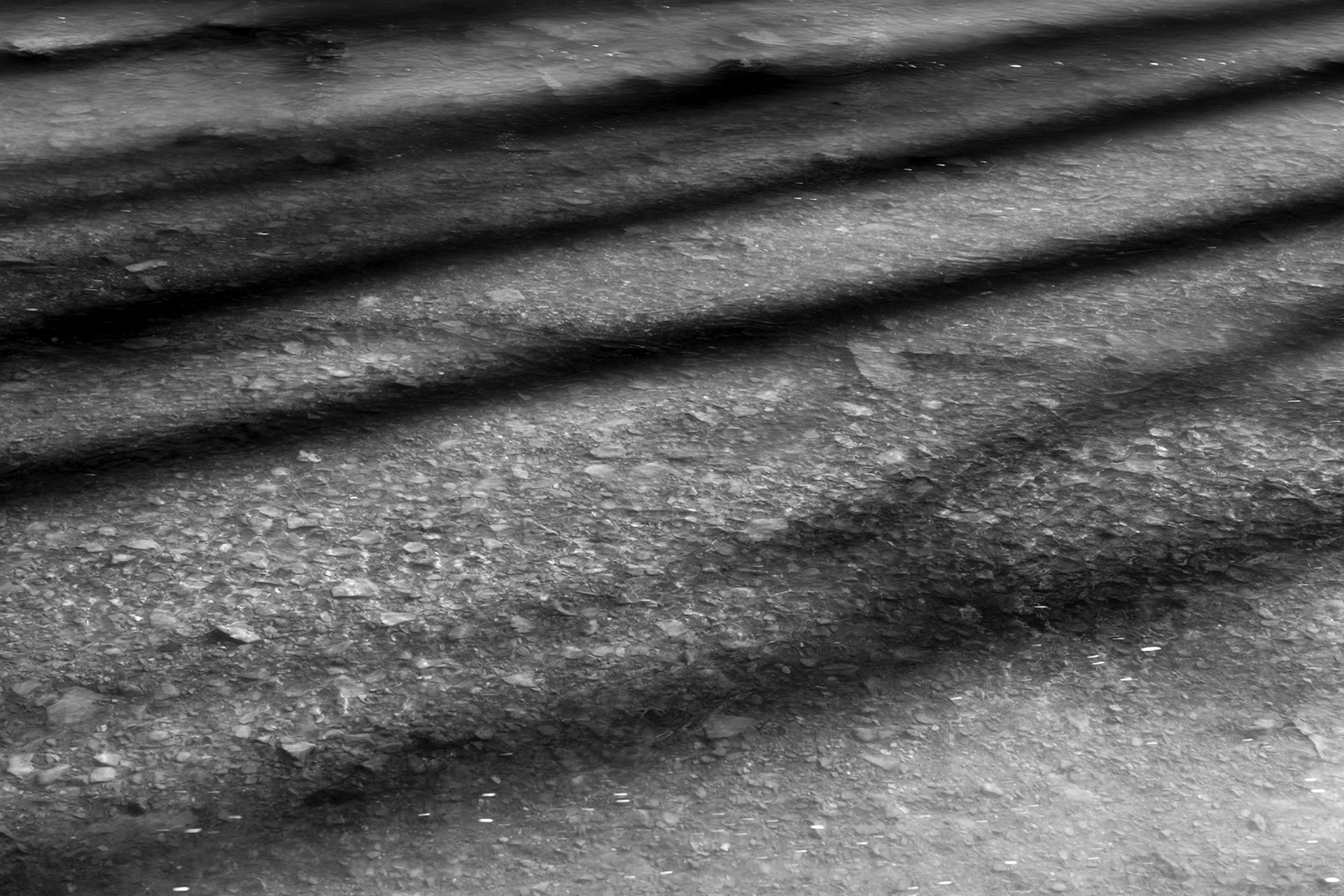 Light and shadow moving across the surface of a stream. Abstract water photograph by Bucchianeri.