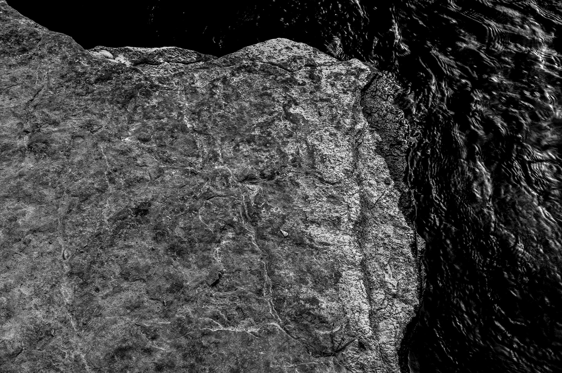 Stone textures and mirrored currents forming a natural abstraction. Photographic work by Ryan Bucchianeri, visual artist.