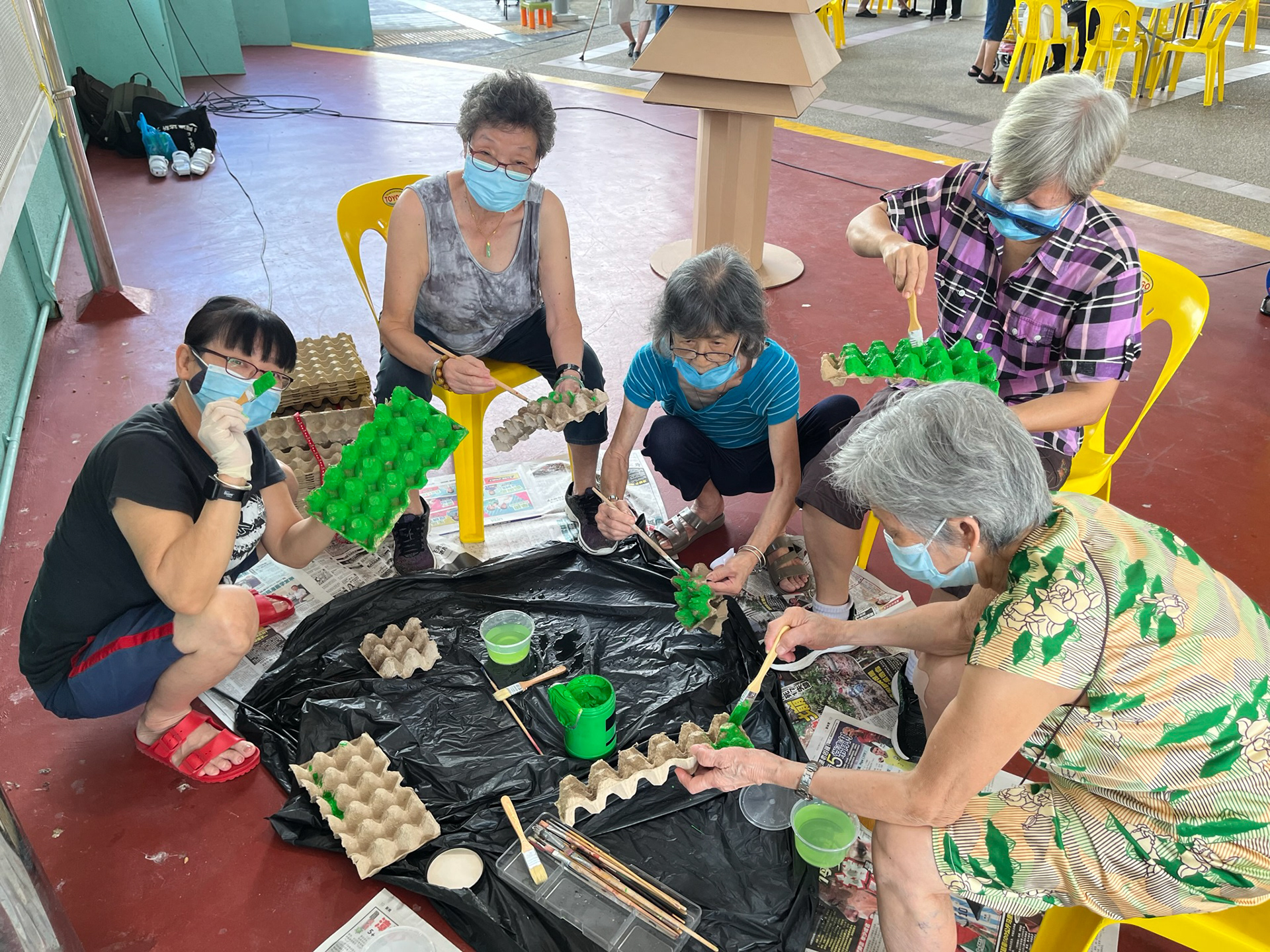 Seniors from the surrounding neighbourhood painting the egg cartons.
