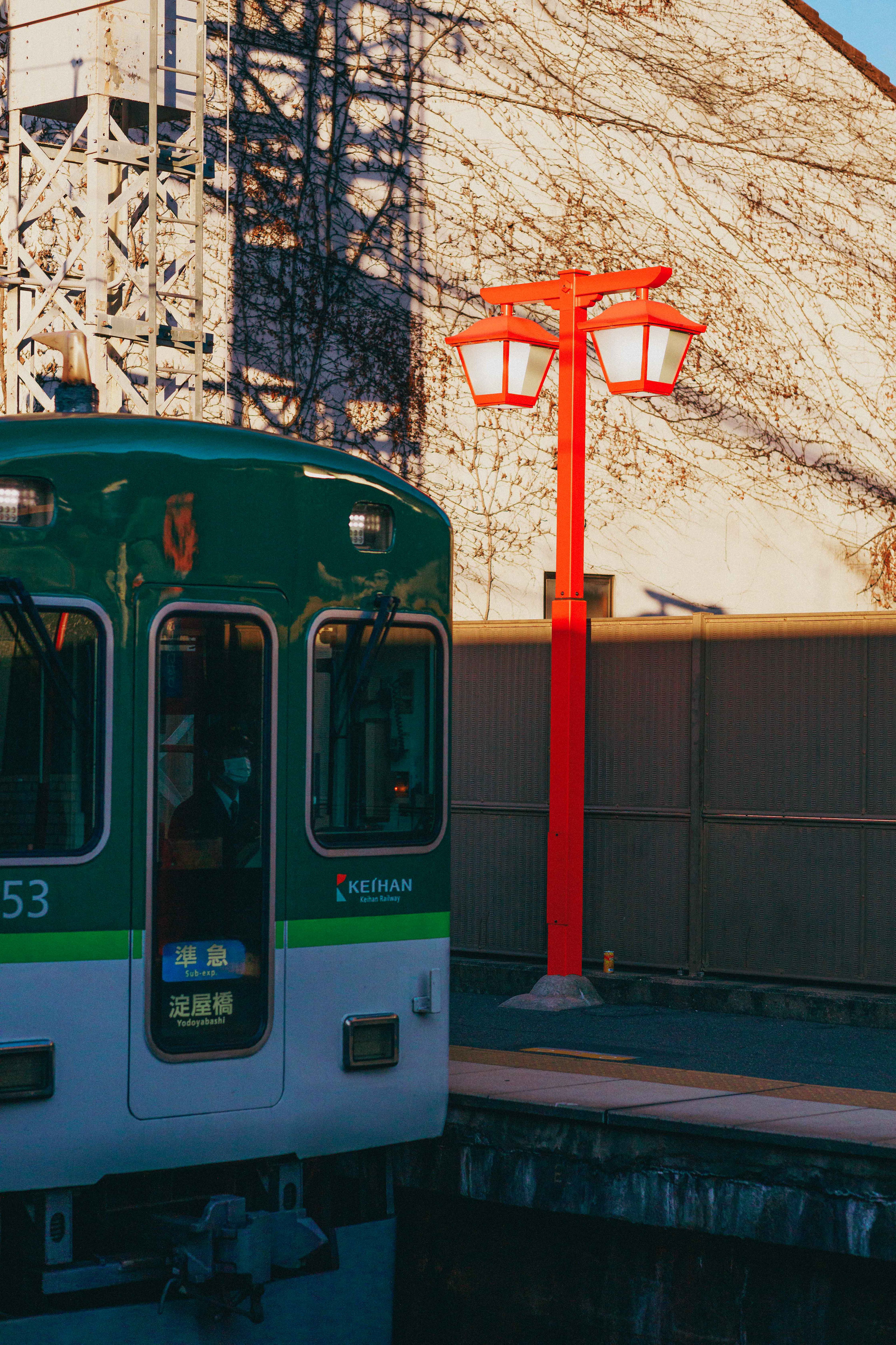 A Lantern at the train station of the Fushimi Inari Taisha Shrine in Kyoto with a train passing by.