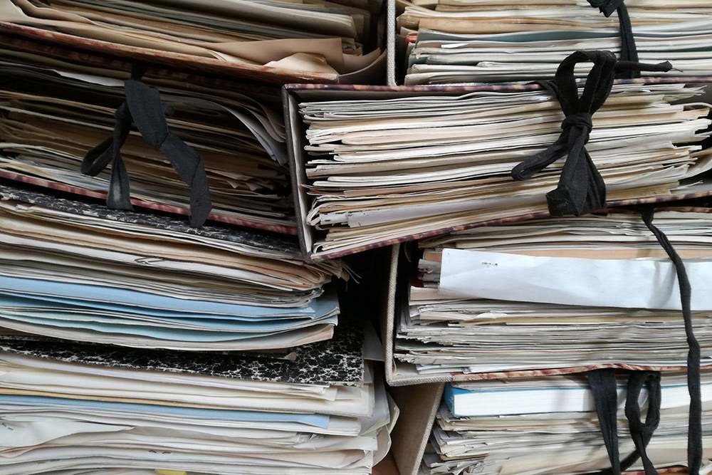 Stack of papers in albums to reflect a writer's hoards of industry-related resources.