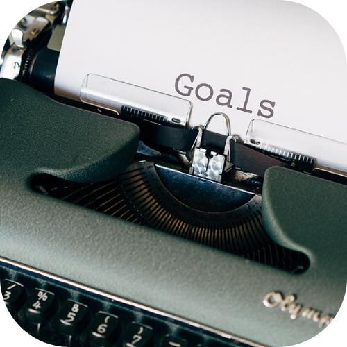 Typewriting typing the word "Goals" on a white paper.