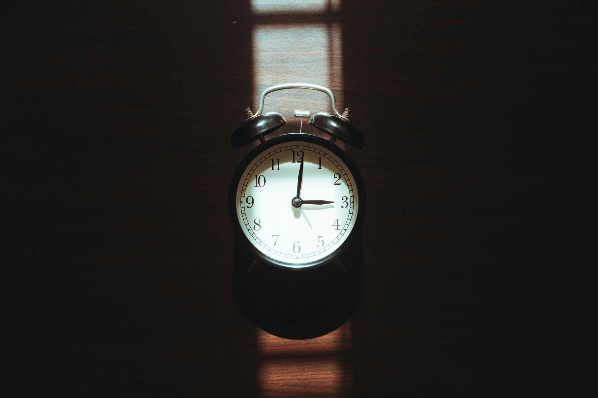 Antique clock pointing at 3 o'clock with striking lighting.