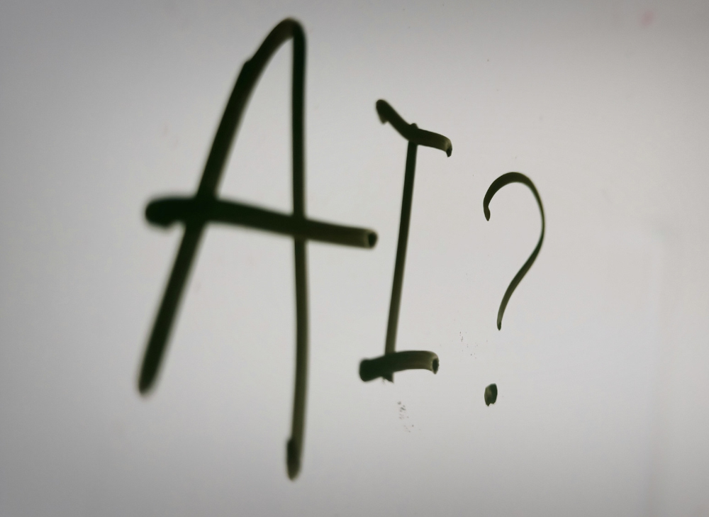 The word "AI?" written on a whiteboard.