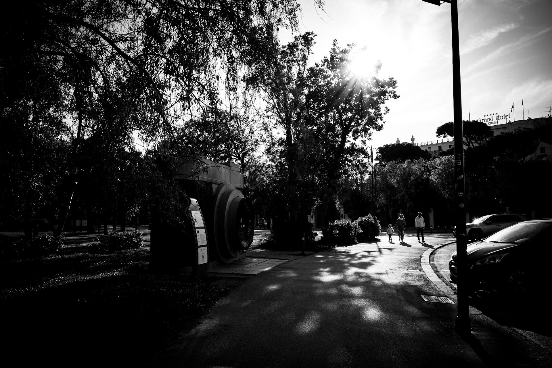 Three people walking in unison toward a light source in a city street, black and white photo, poetic urban mood