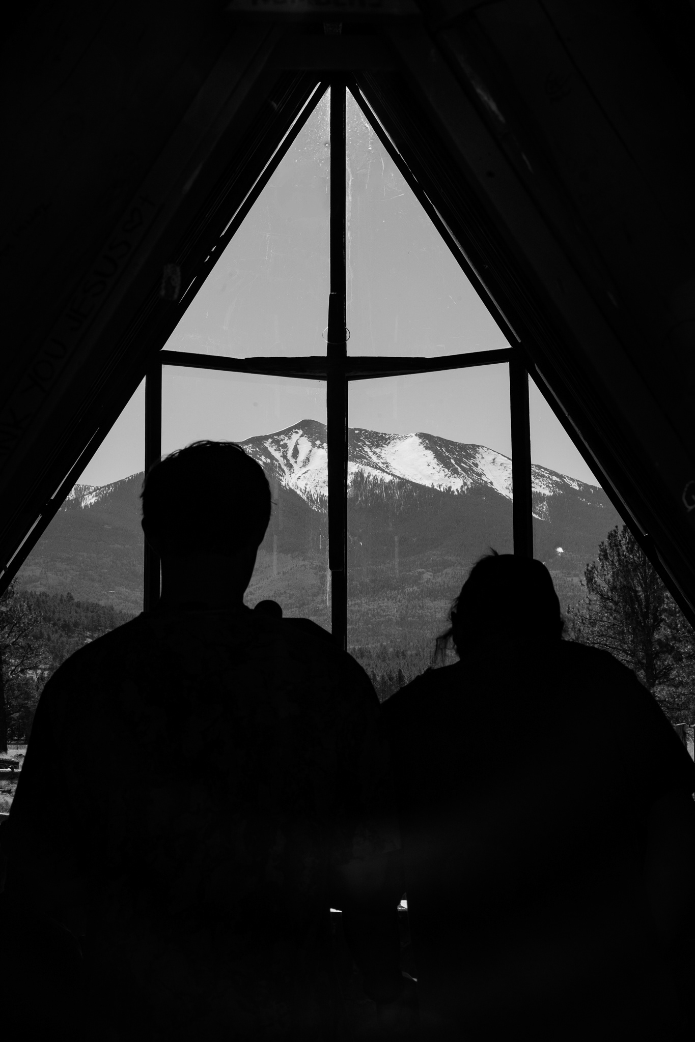 Cinematographers Parker Hall and Rob Burtla compose a photo inside of The Chapel of The Holy Dove. When we moved inside to shoot this scene, the first thing that immediately caught my attention was the way that the window was positioned. Right in the background, it was the snow on the top of the mountain. It popped off of the screen super well. And to really highlight that while also showing the things that are happening inside of the church. Taken on the Canon EF 70-200 f/2.8. March 21, 2026. 