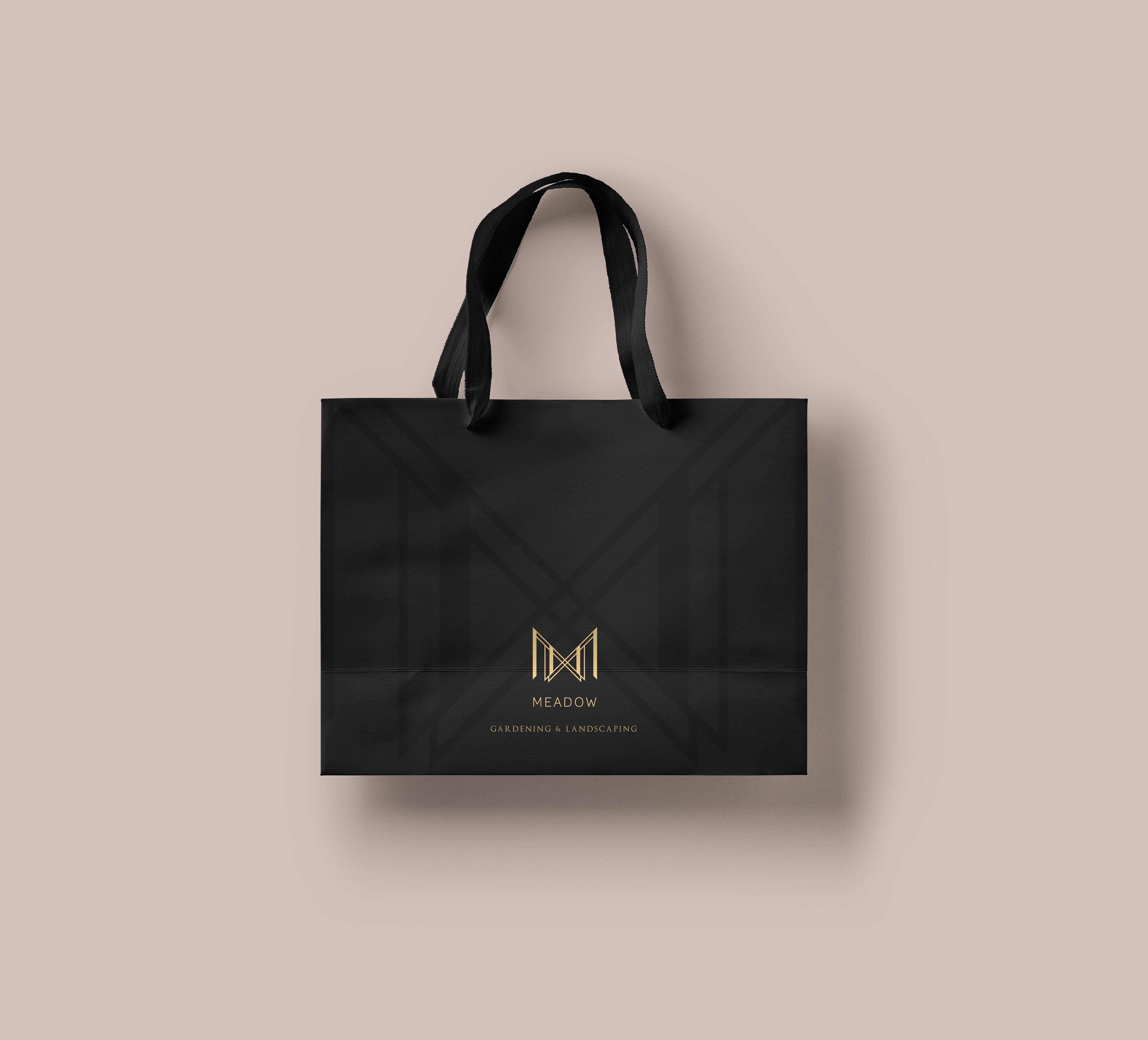 Gardening gold foil logo design of a geometric shape M letter on a charcoal black paper bag - top logo designers in Kuwait