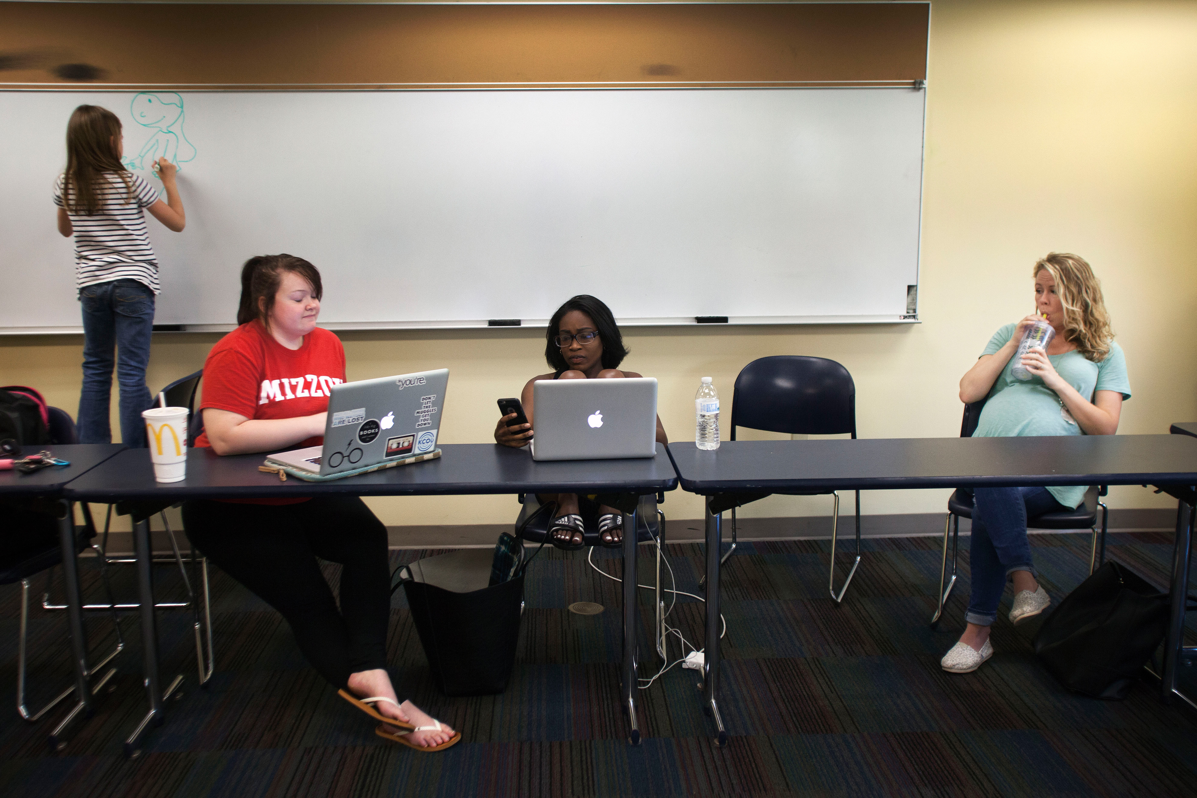 Haylie Payne, 8, left, draws on the white board while her mother and classmates work on their capstone project in Strategic Communications in Responsibility Hall on Sunday, April 24, 2016. Since Traci's husband works odd hours, she often has to bring Haylie along to her classes. "Haylie was a real trooper this year," Traci said. "I hope that she will one day remember how hard I worked for my education and be inspired to do the same."