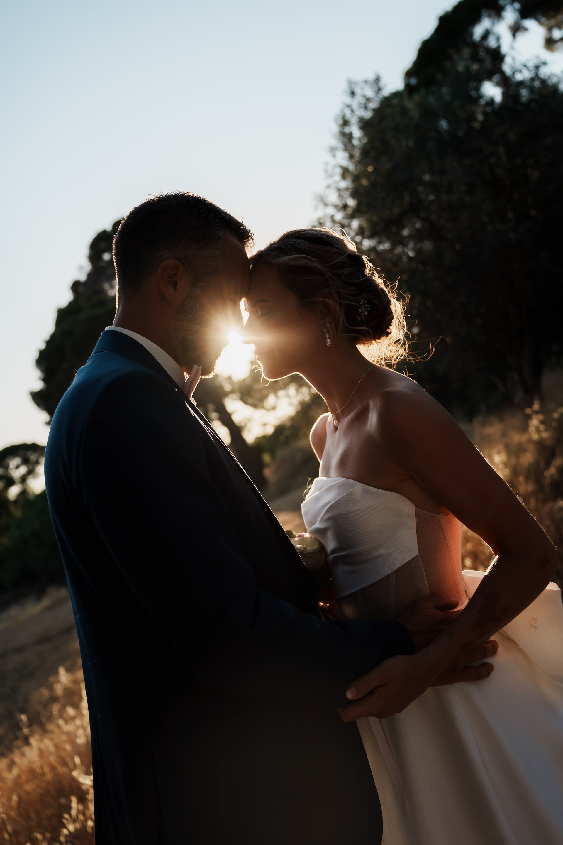Couple face à face au coucher de soleil avec un rayon de lumière entre leurs visages pendant la séance photo