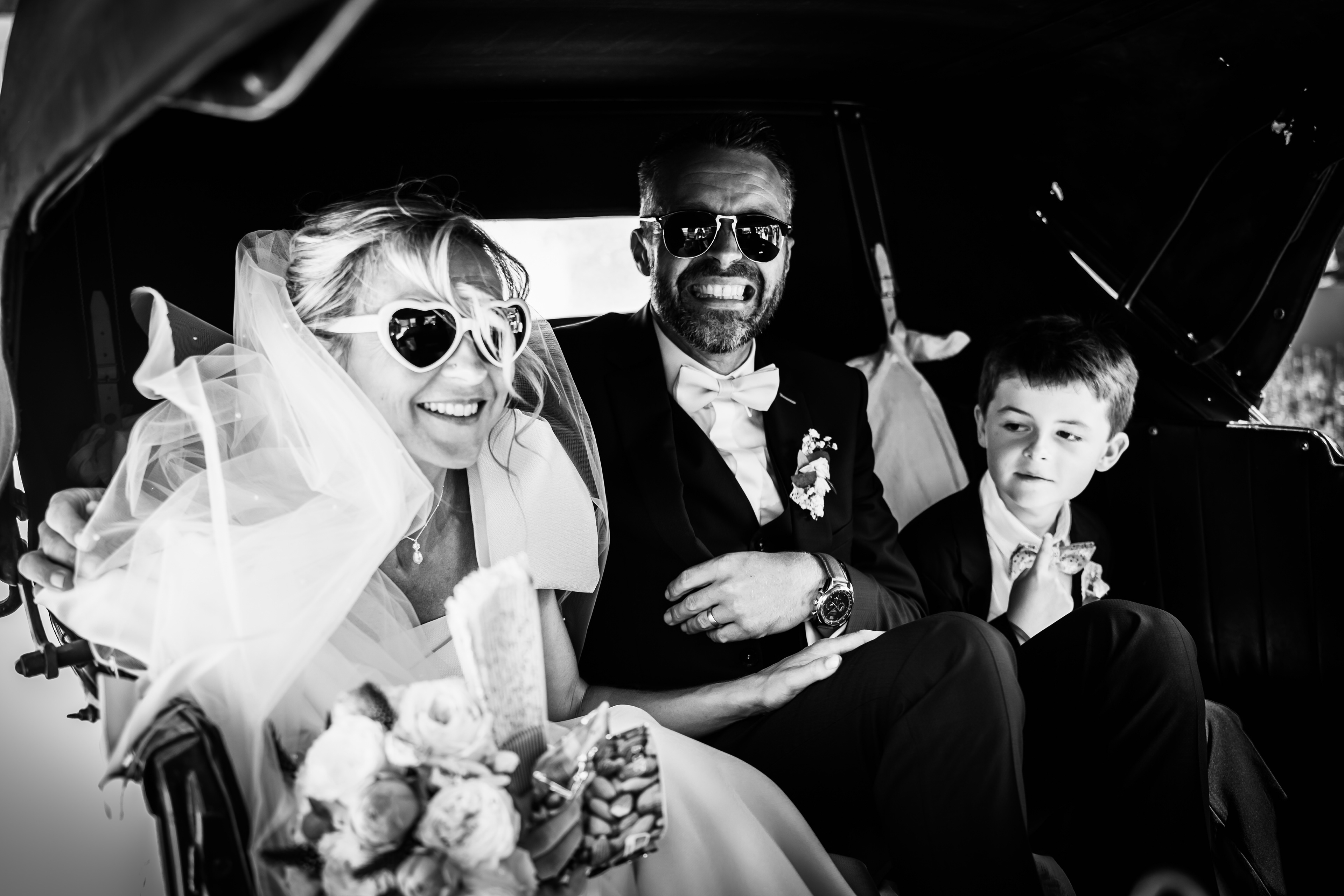 Les mariés dans une voiture en noir et blanc après la cérémonie de mariage à Béziers