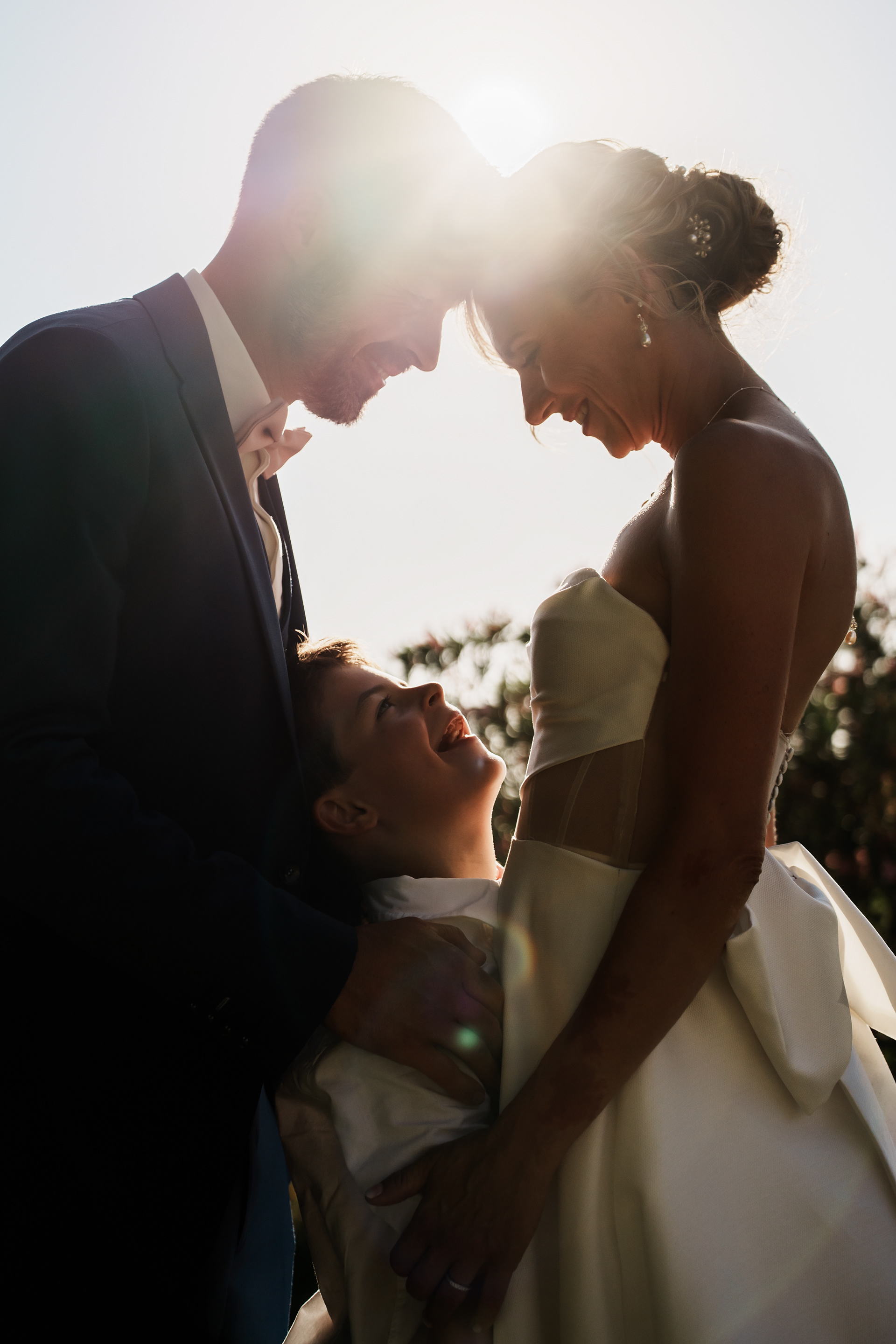 Les mariés et leur fils face à face dans une lumière chaude lors de la séance photo au Domaine de l’Ale à Capestang dans l’Hérault