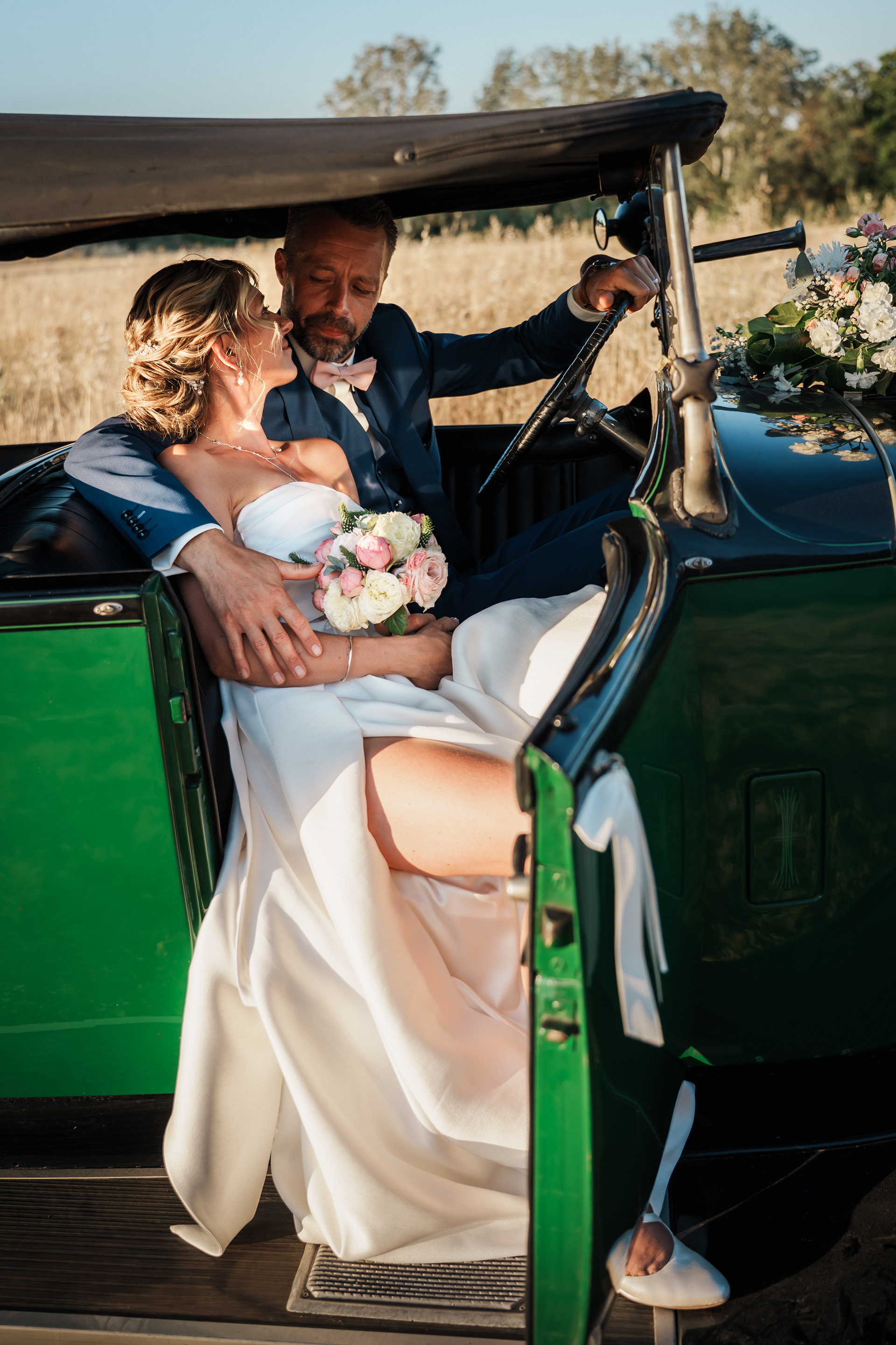 Les mariés dans une voiture de collection au coucher de soleil au Domaine de l’Ale à Capestang dans l’Hérault