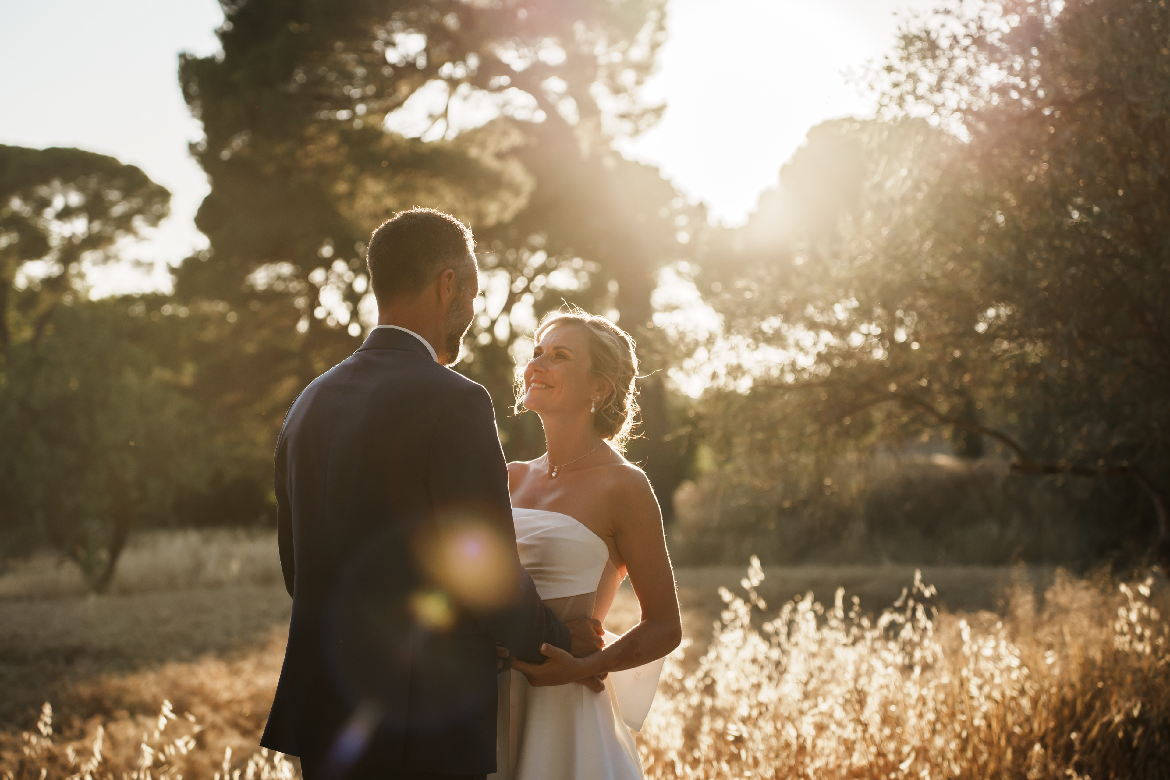 Les mariés se regardent face à face au coucher de soleil pendant leur séance photo de mariage