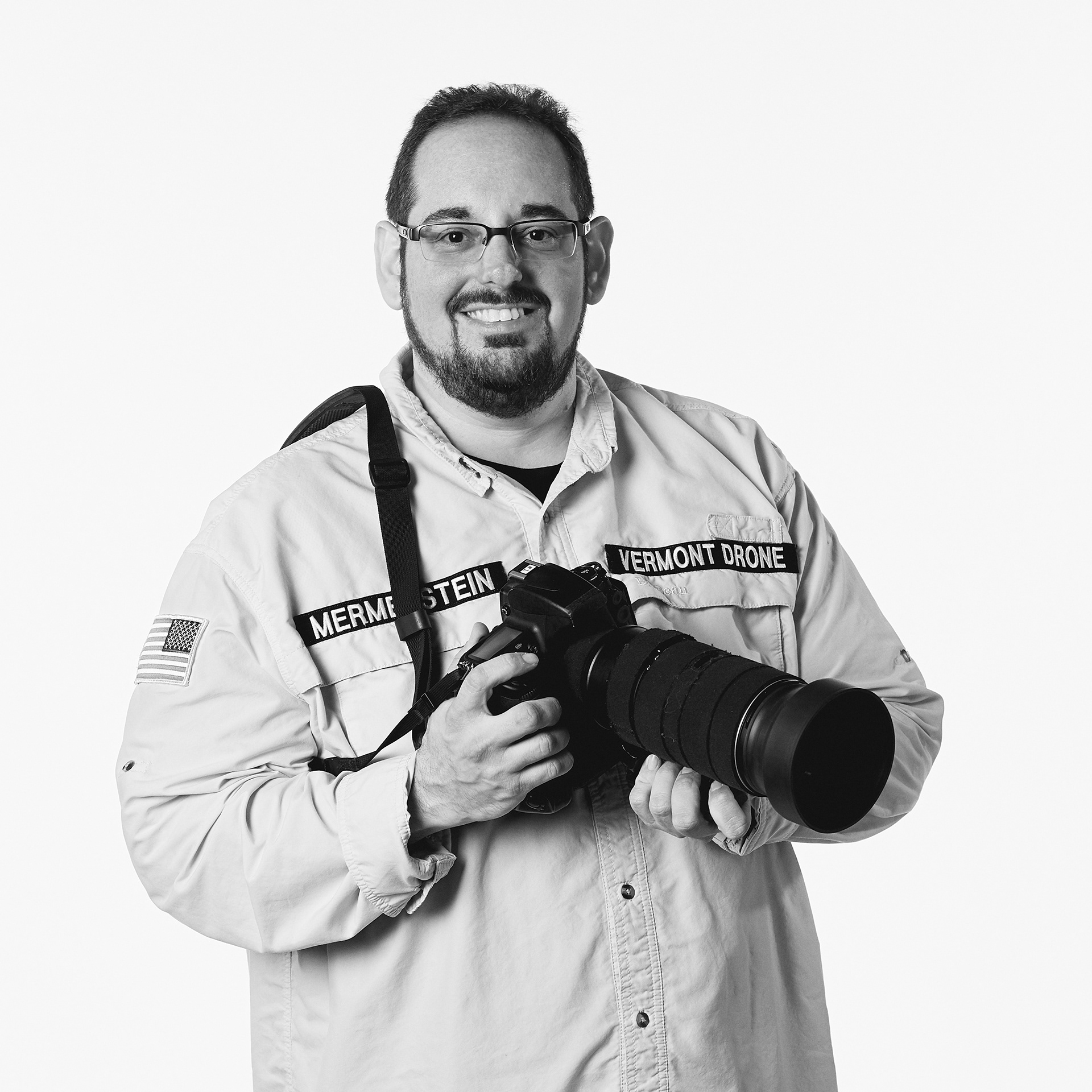 Photograph of Vermont Photographer and Cinematographer Steve Mermelstein holding a DSLR camera with a long lens.