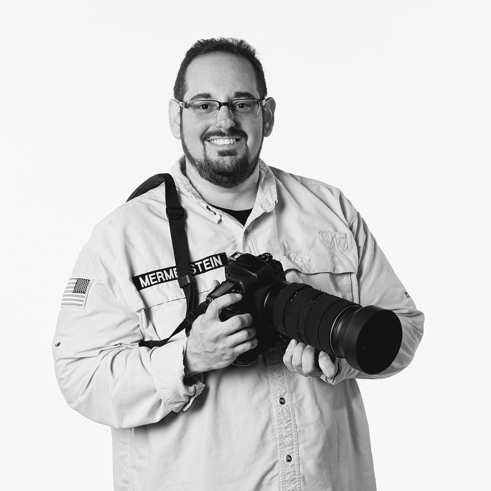 Photograph of Vermont Photographer and Cinematographer Steve Mermelstein holding a DSLR camera with a long lens.