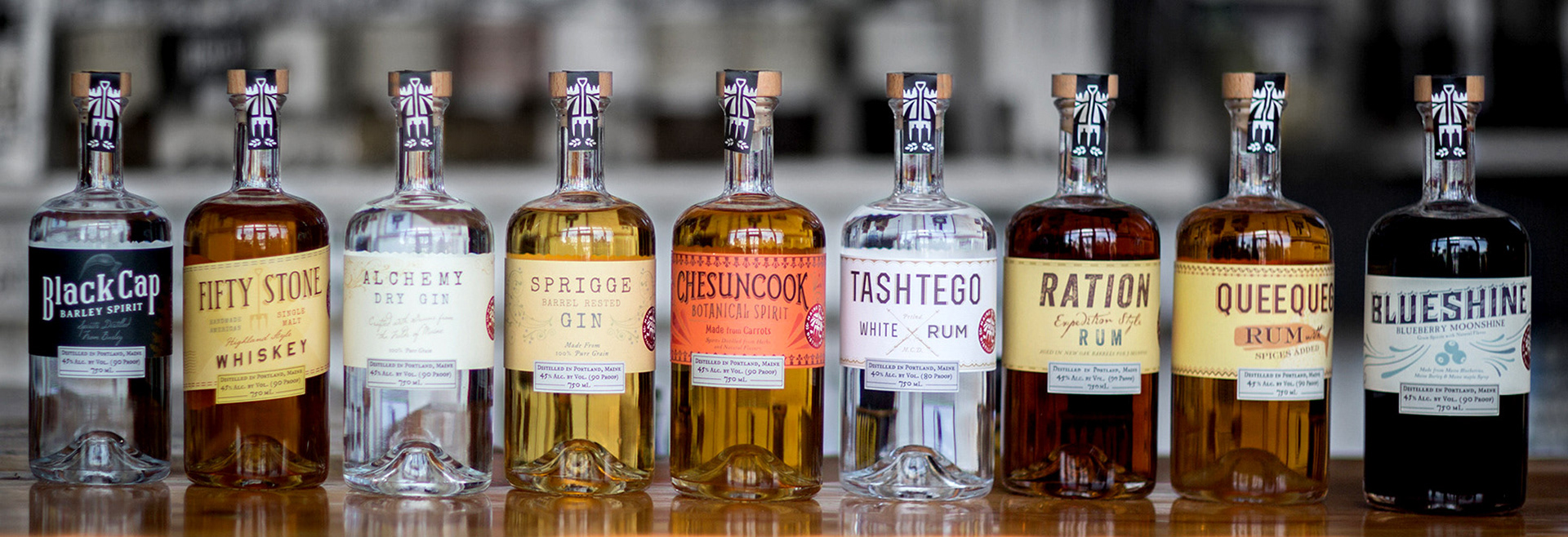 Photo of a row of liquor bottles and labels for Maine Craft Distilling