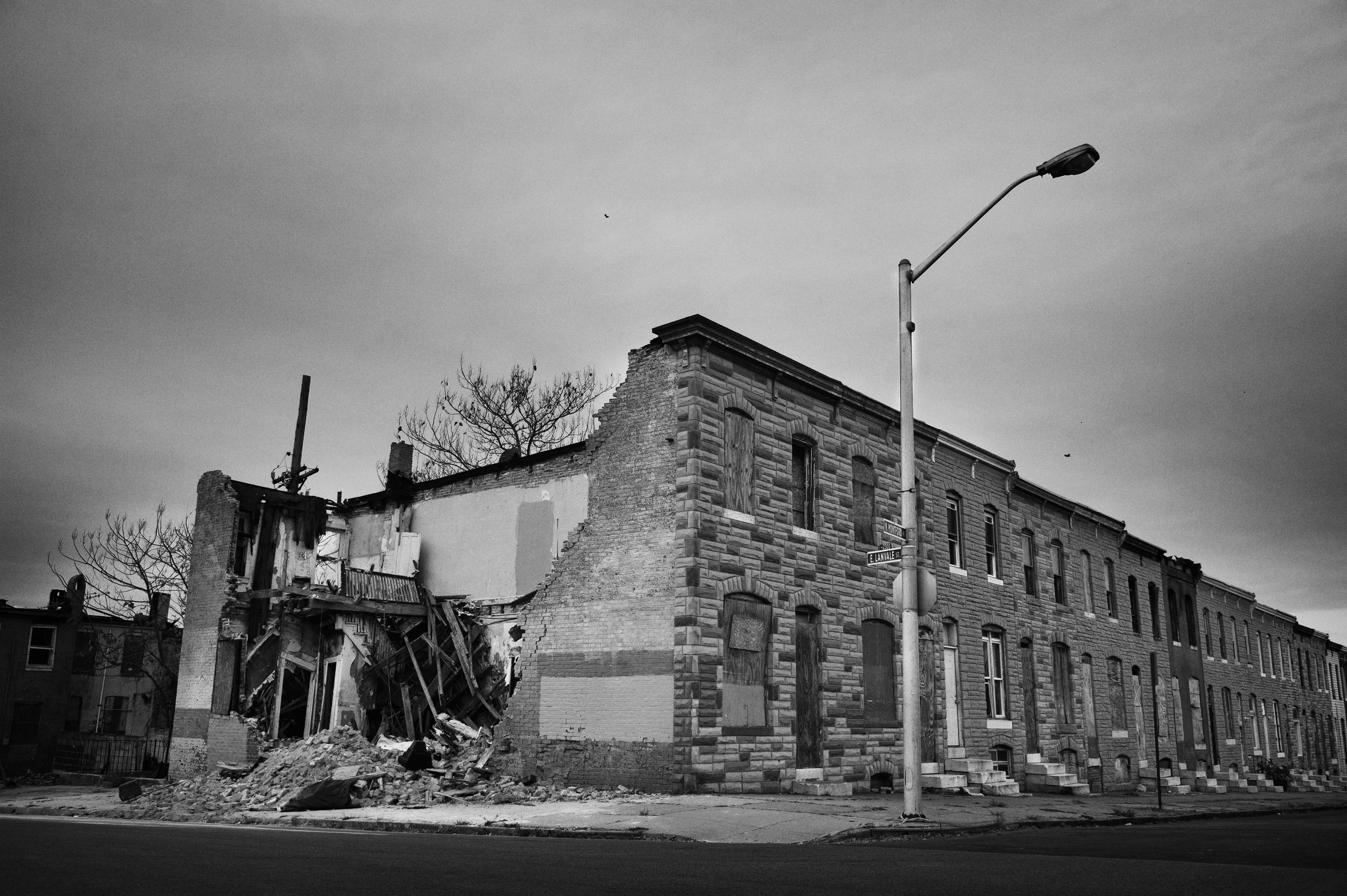 Rows of boarded-up houses stretch into the distance as a collapsed building exposes the fragile state of a once-thriving neighborhood. Baltimore, USA