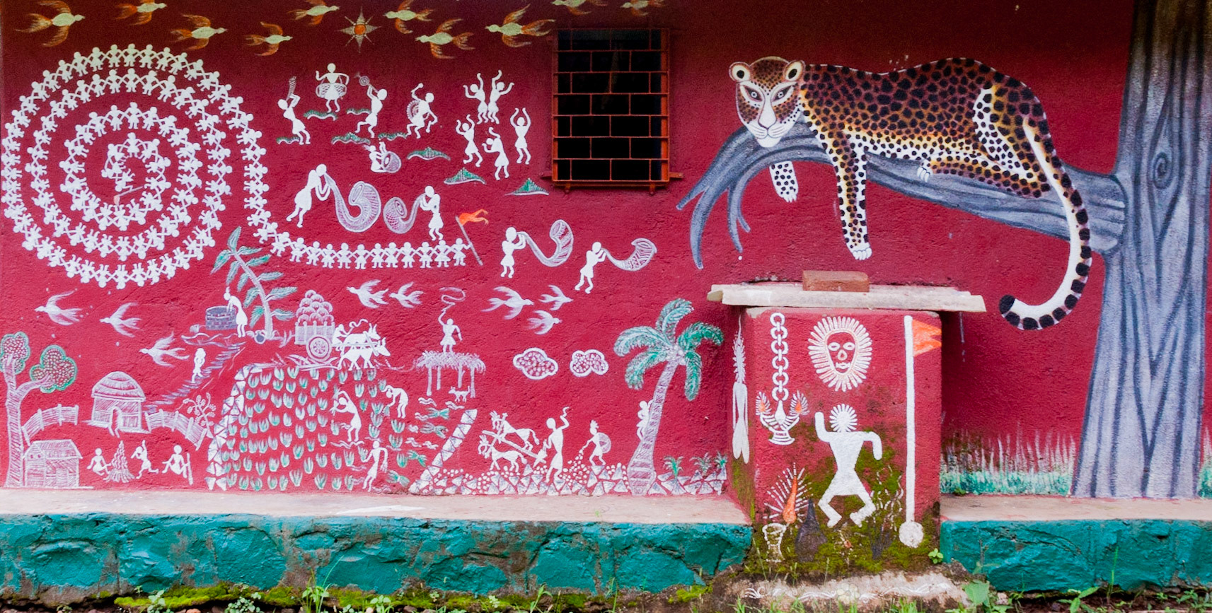 MUMBAI, INDIA – August 9 2018: Mural on Warli temple depicts traditional scenes of farming, domestic animals, music, dance; and a leopard resting on a tree branch.
