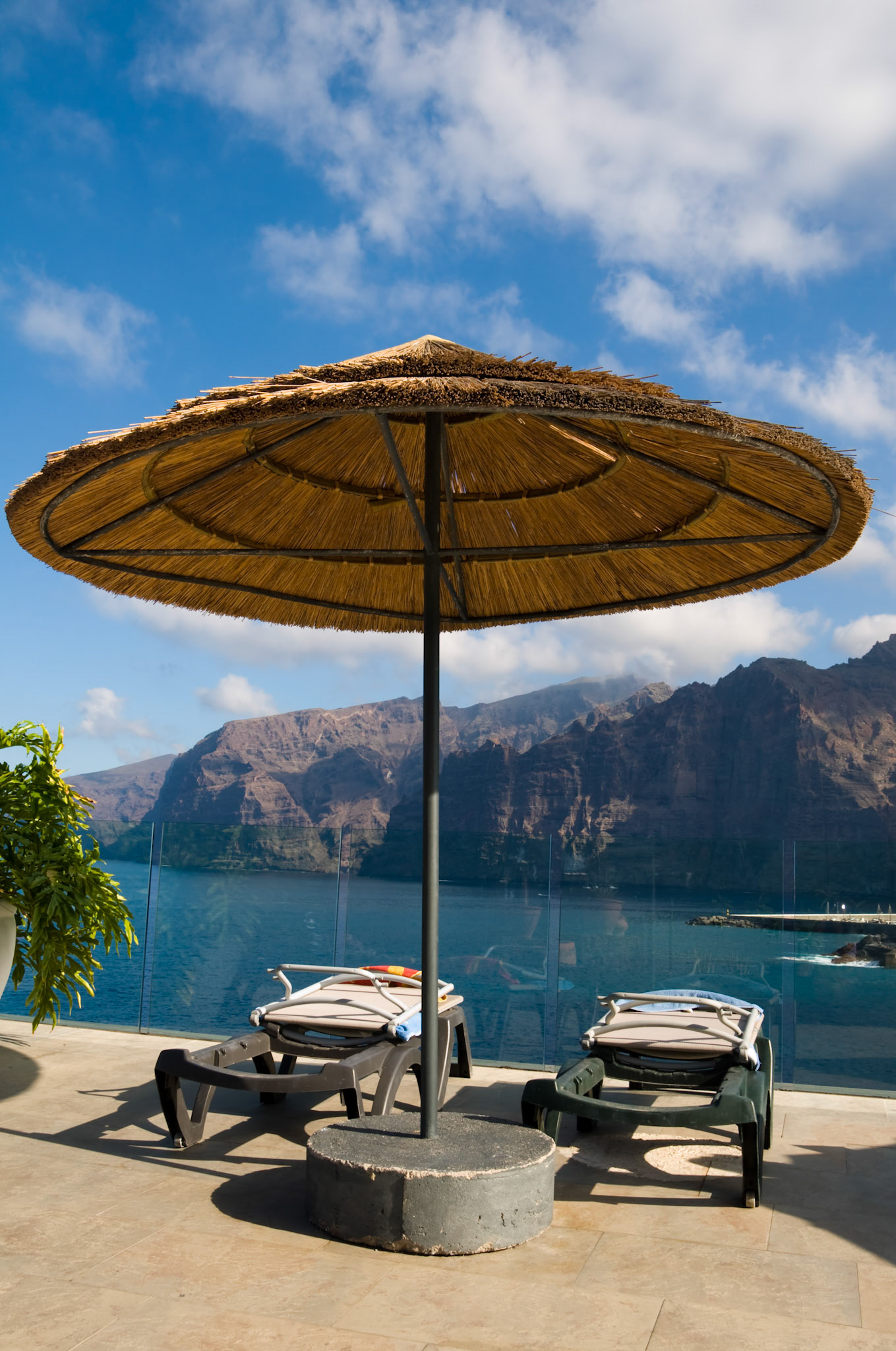 Straw umbrella with sunbeds with a nice view to the mountains and ocean