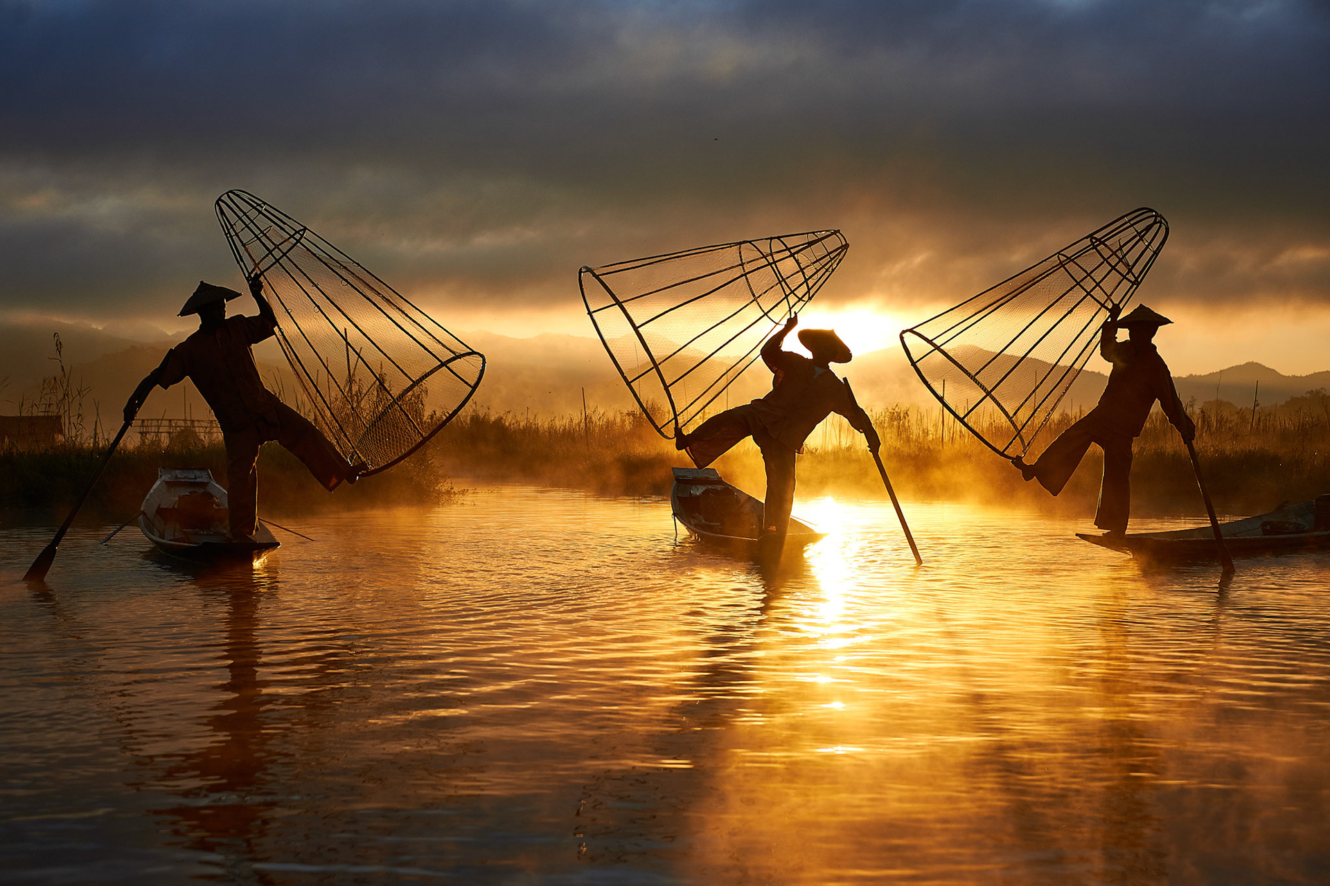 Three fisherman from Myanmar with fishnets at sunrise