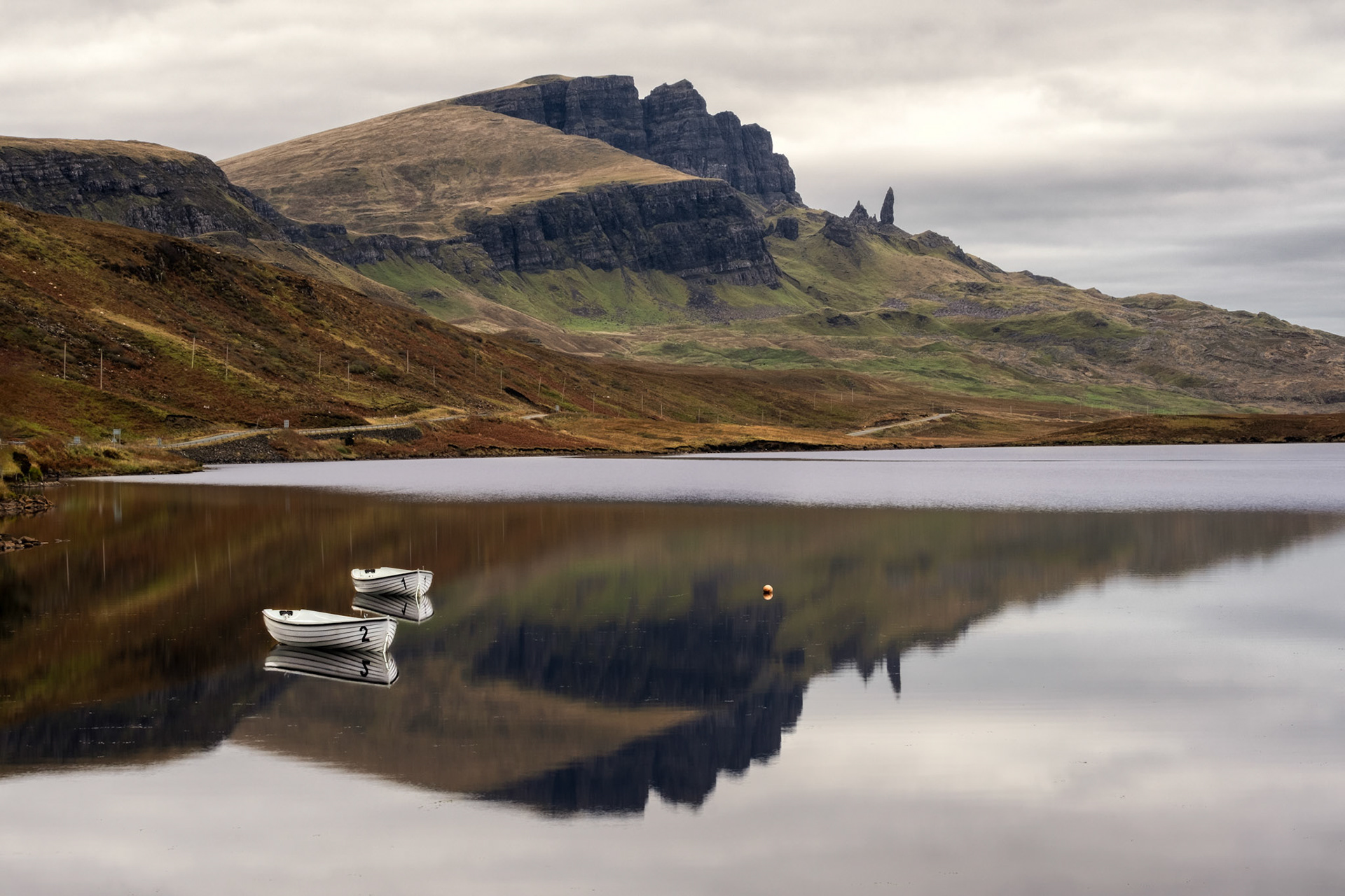 Two boats with the Old Man of Storr reflecte on the lake