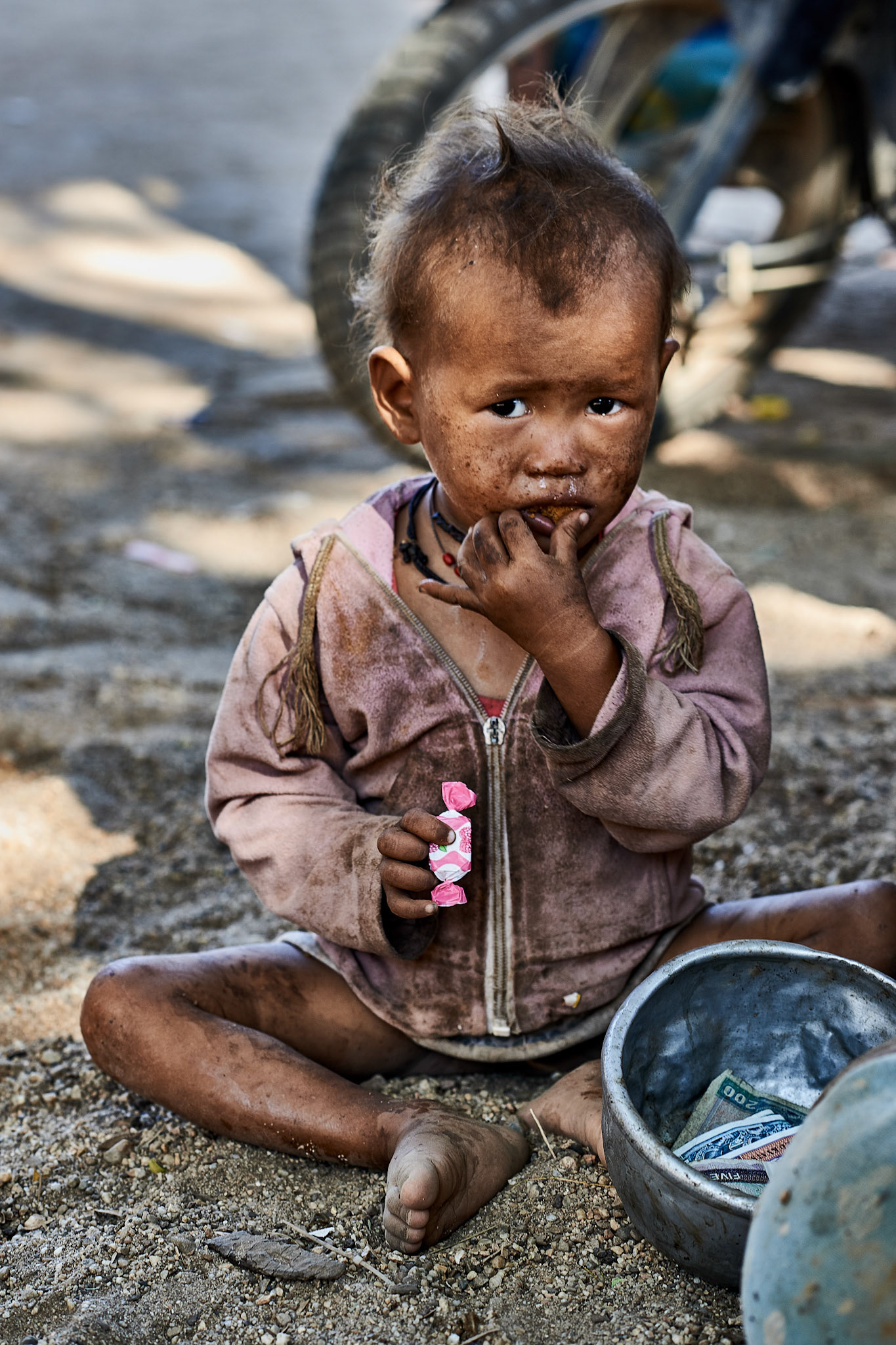 From all the children I've seen in Myanmar, this little one was by far the dirtiest. I met her in front of a temple gate with her mother, who was as dirty as her daughter. I offered her some sweets and she immediately took them and went back to her sit. I left the place with a sad feeling. However, when I was back home I had a chat with my 6yo daughter about this photo:Me: : What do you think about this little girl?  Is she poor or rich? She: She is rich !” Me: How did you reach to this conclusion?She: Look mommy, she has money!To such an direct and blunt answer I was speechless.