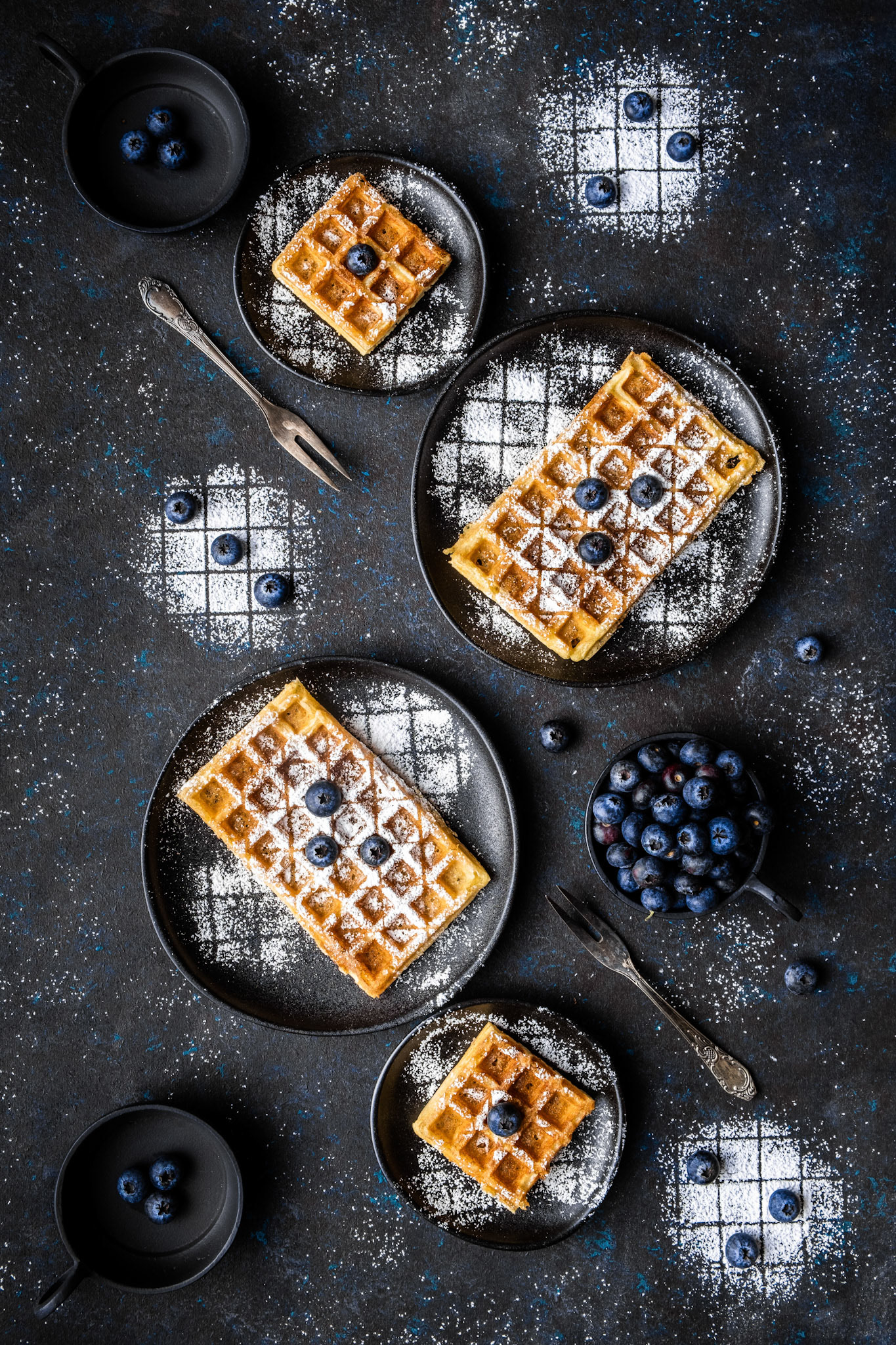 Sourdough waffles dusted with sugar and with blueberries as toppings