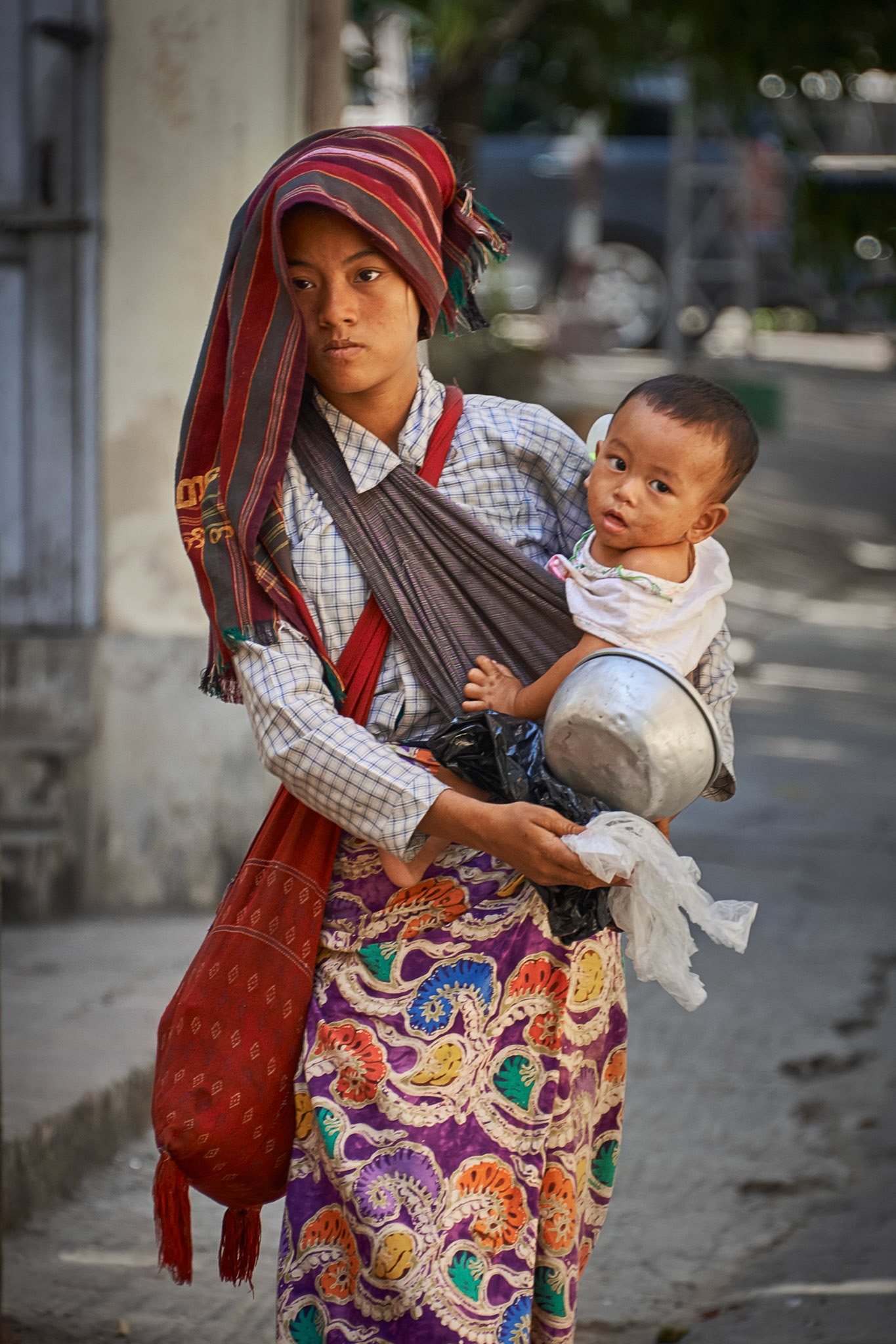 After the monks line up for lunch, the tourists spread all over the city. Few locals continue their daily routine. Exactly like this mom begging to feed her child.