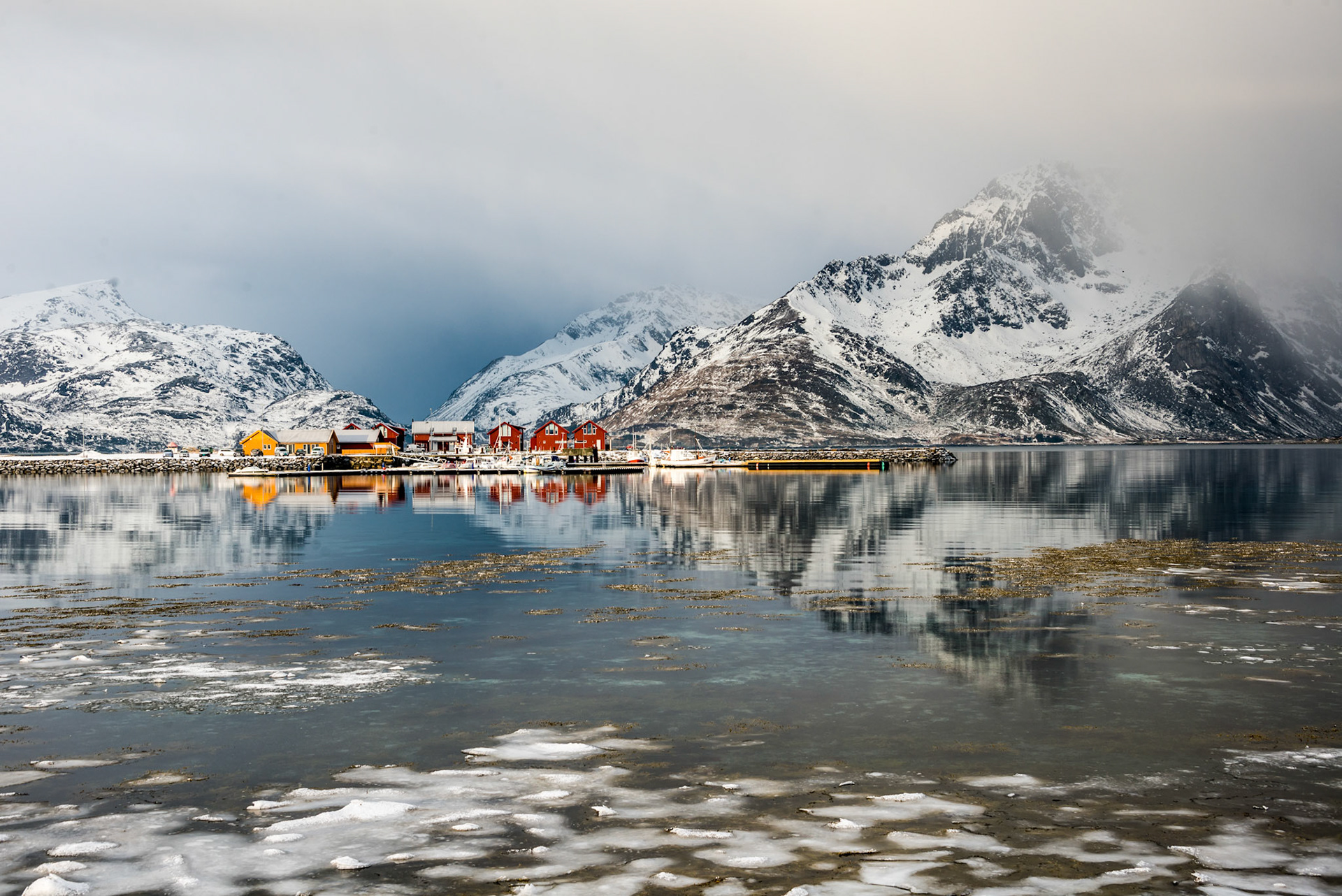 Scenery with reflected cottages in Lofoten, Norway before snow storm