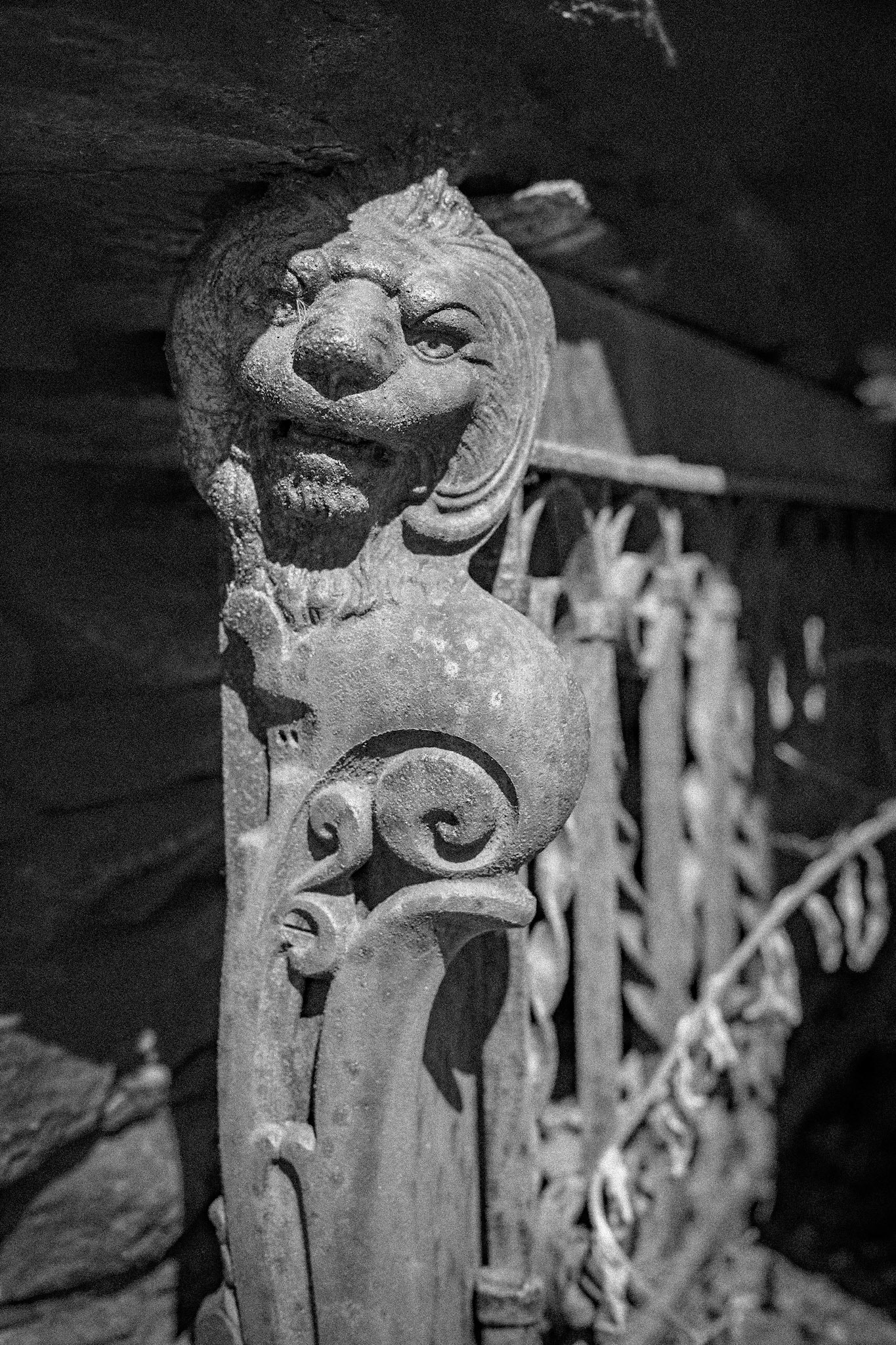 A cast iron lion on the end of an antique mantelpiece that has been left to rust in a stone grotto.