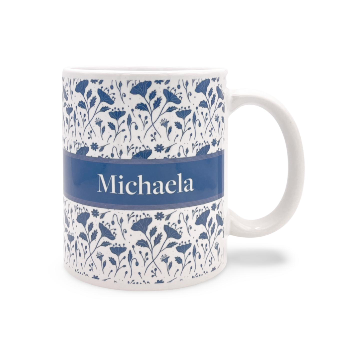 Weiße Tasse mit blauem Blumenmuster und dem Namen 'Michaela' auf blauem Hintergrund