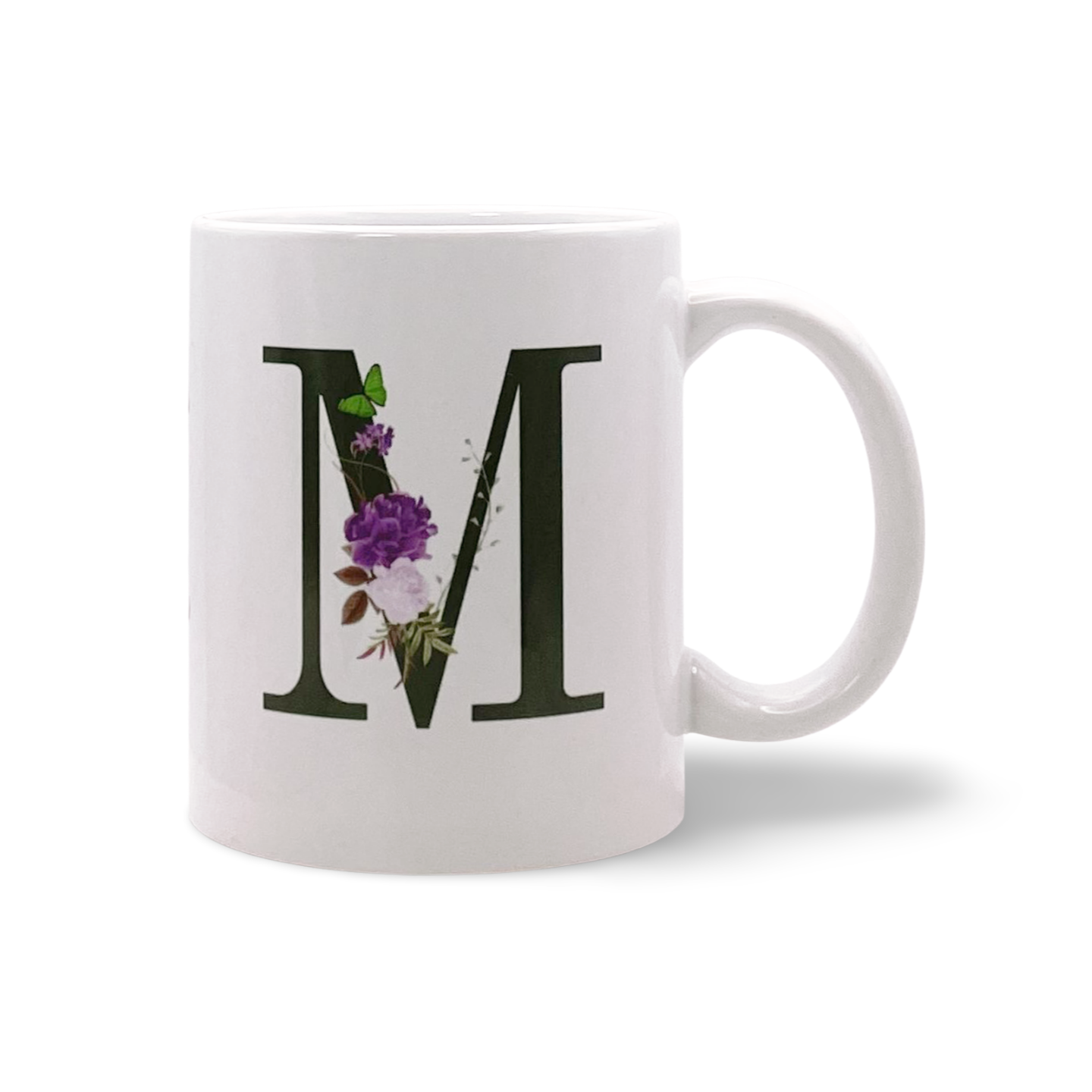 Weiße Tasse mit großem Buchstaben M, der mit einer lila Blume und einem grünen Schmetterling verziert ist