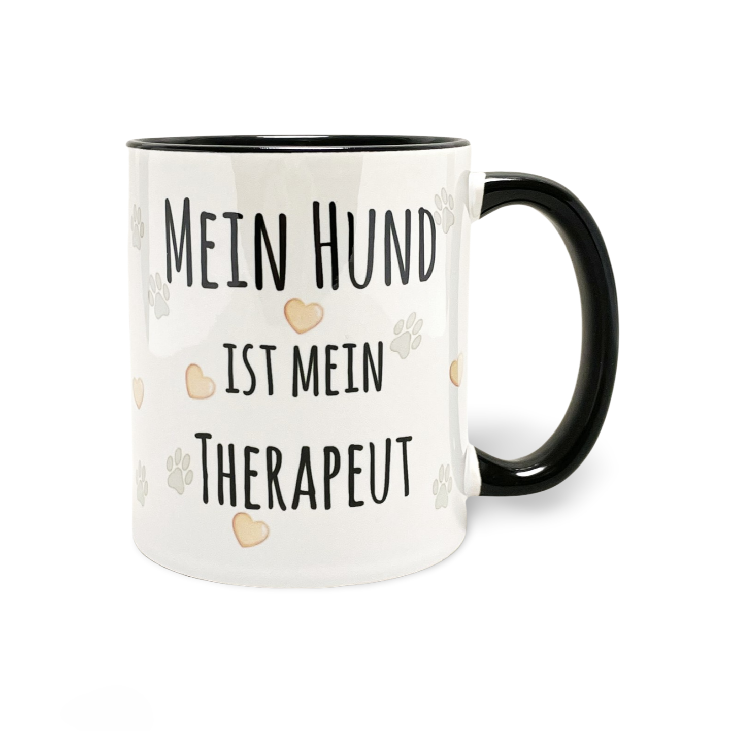 Weiße Tasse mit schwarzem Henkel und der Aufschrift 'MEIN HUND IST MEIN THERAPEUT' umgeben von Pfoten- und Herzmotiven