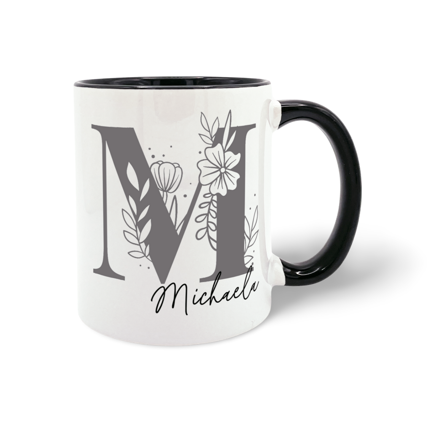 Weiße Tasse mit schwarzem Henkel und großem Buchstaben , verziert mit floralen Elementen und dem Schriftzug 'dein Name'