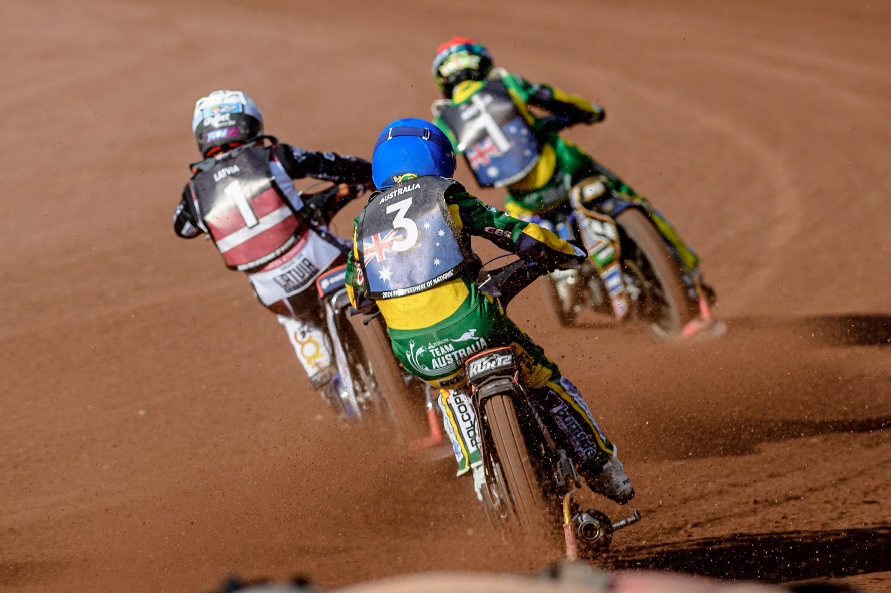 Brady Kurtz of Australia in Blue chases Andzejs Lebedevs of Latvia in White and Jack Holder of Australia in Red during the Monster Energy FIM Speedway of Nation Final at the National Speedway Stadium, Manchester on Saturday 13th July 2024. (Photo: Ian Charles | MI News)