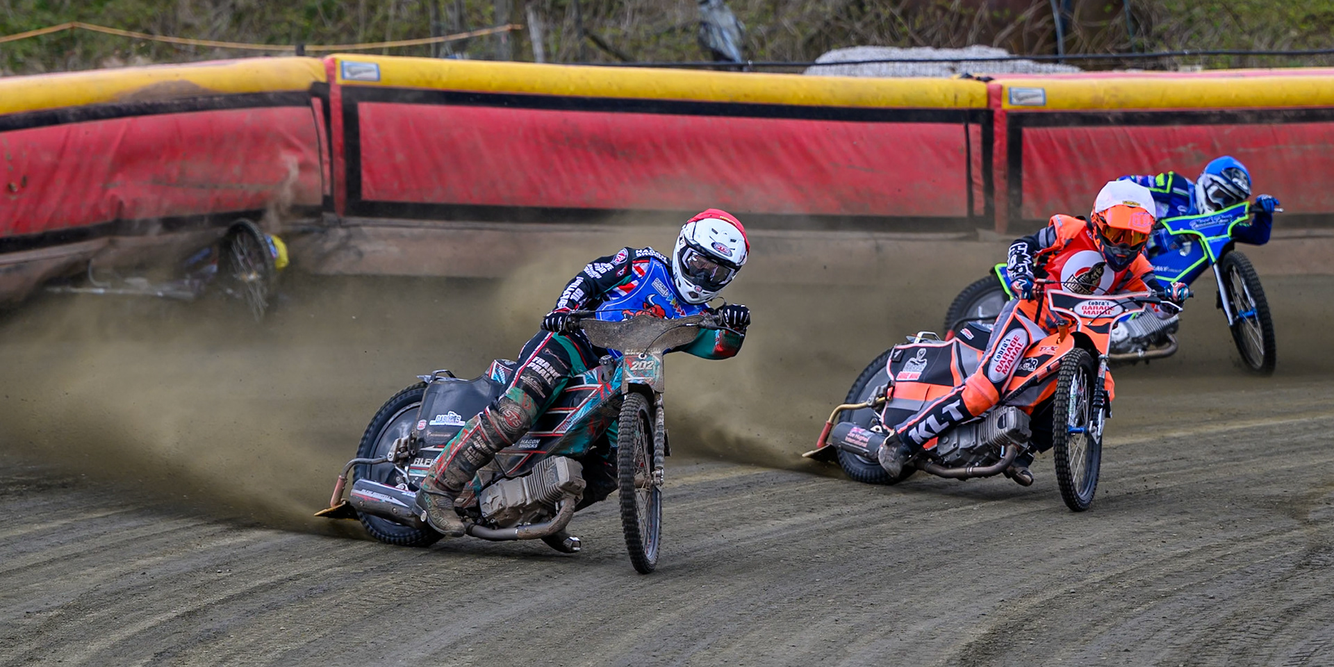 Alfie Bowtell of Buxton Bulls  in Red Connor Coles of NDL Nomads in White as Sam Woods of NDL Nomads  slides into the safety fence as Arran Butcher of Buxton Bulls  spins his machine during the  Challenge match between Buxton Bulls and NDL Nomads at Hi-Edge Speedway, Buxton on Sunday 19th April 2026. (Photo: Ian Charles | MI News)
