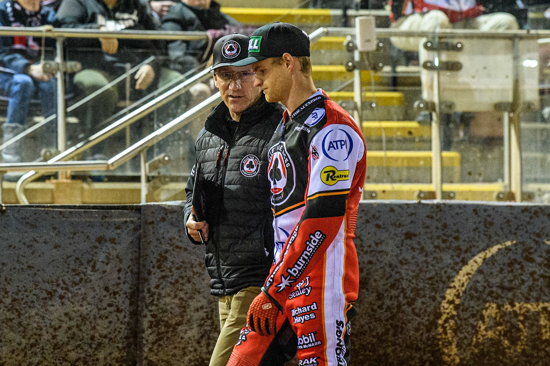 Mark Lemon Team Manager of Belle Vue Aces (Left) chats with Brady Kurtz  as they walk back to the pits during the Premiership Cup Quarter Final 1st Leg match between Belle Vue Aces and Ipswich Witches at the National Speedway Stadium, Manchester on Monday 24th March 2025. (Photo: Ian Charles | MI News)