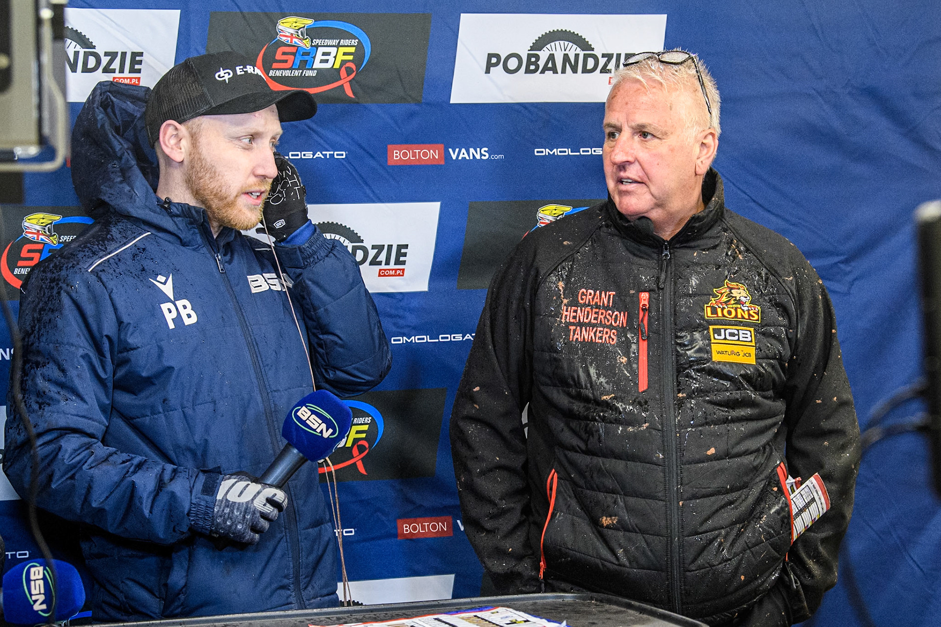 Stewart Dickson, Team Manager of Leicester Lions (Right) waits to be interviewed by Paul Bowen of BSN during the Rowe Motor Oil Premiership match between Belle Vue Aces and Leicester Lions at the National Speedway Stadium, Manchester on Saturday 6th April 2024. (Photo: Ian Charles | MI News)