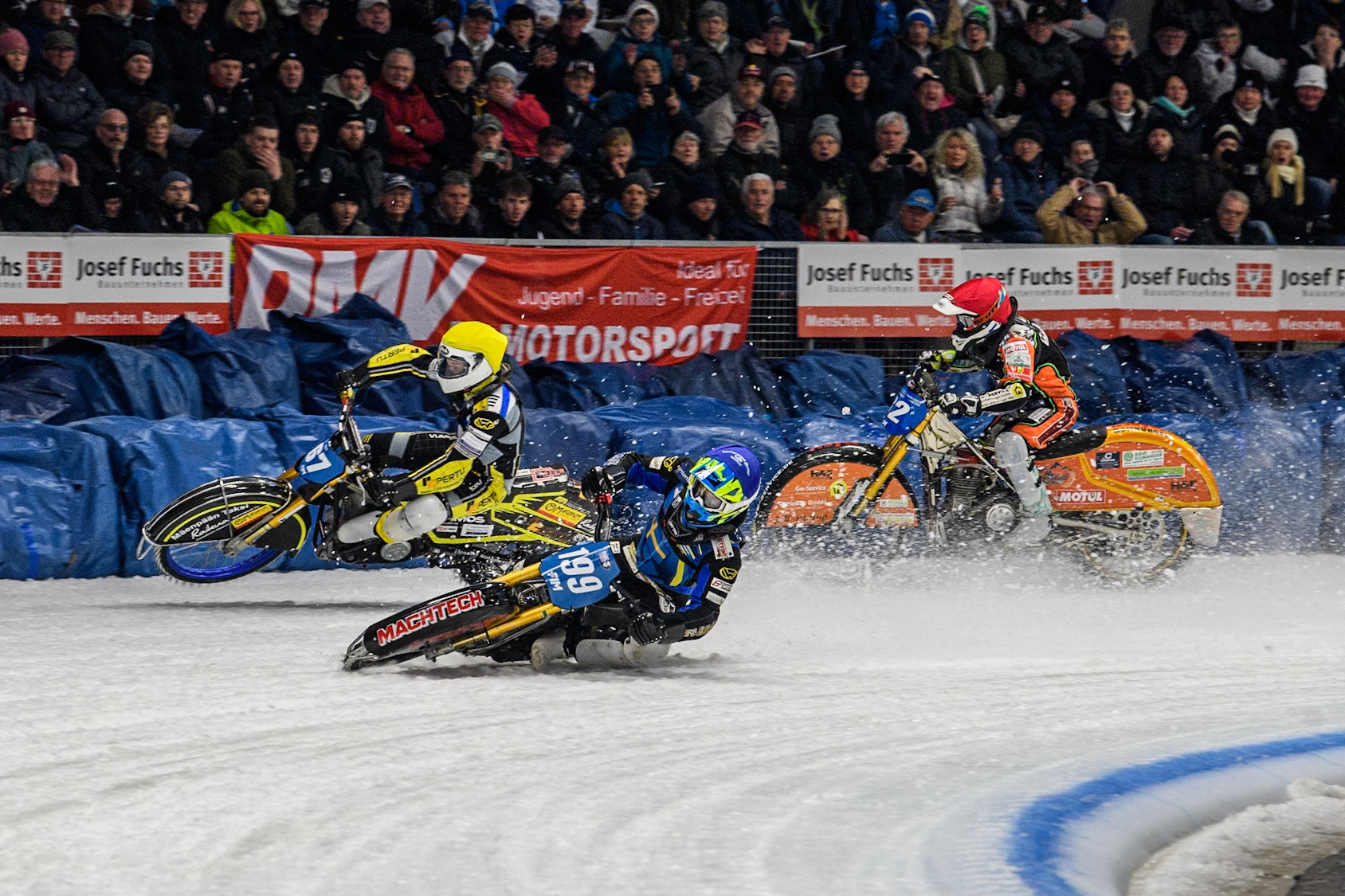 Sweden's Martin Haarahiltunen (199)  (Blue) leads  and Germany's Markus Jell (82) (Red) and Finland's Heikki Huusko (67)y\ collide and crash into the bales during the FIM Ice Speedway Gladiators World Championship Final 2 at the Max-Aicher-Arena, Inzell on Sunday 24 March 2024. (Photo: Ian Charles | MI News)