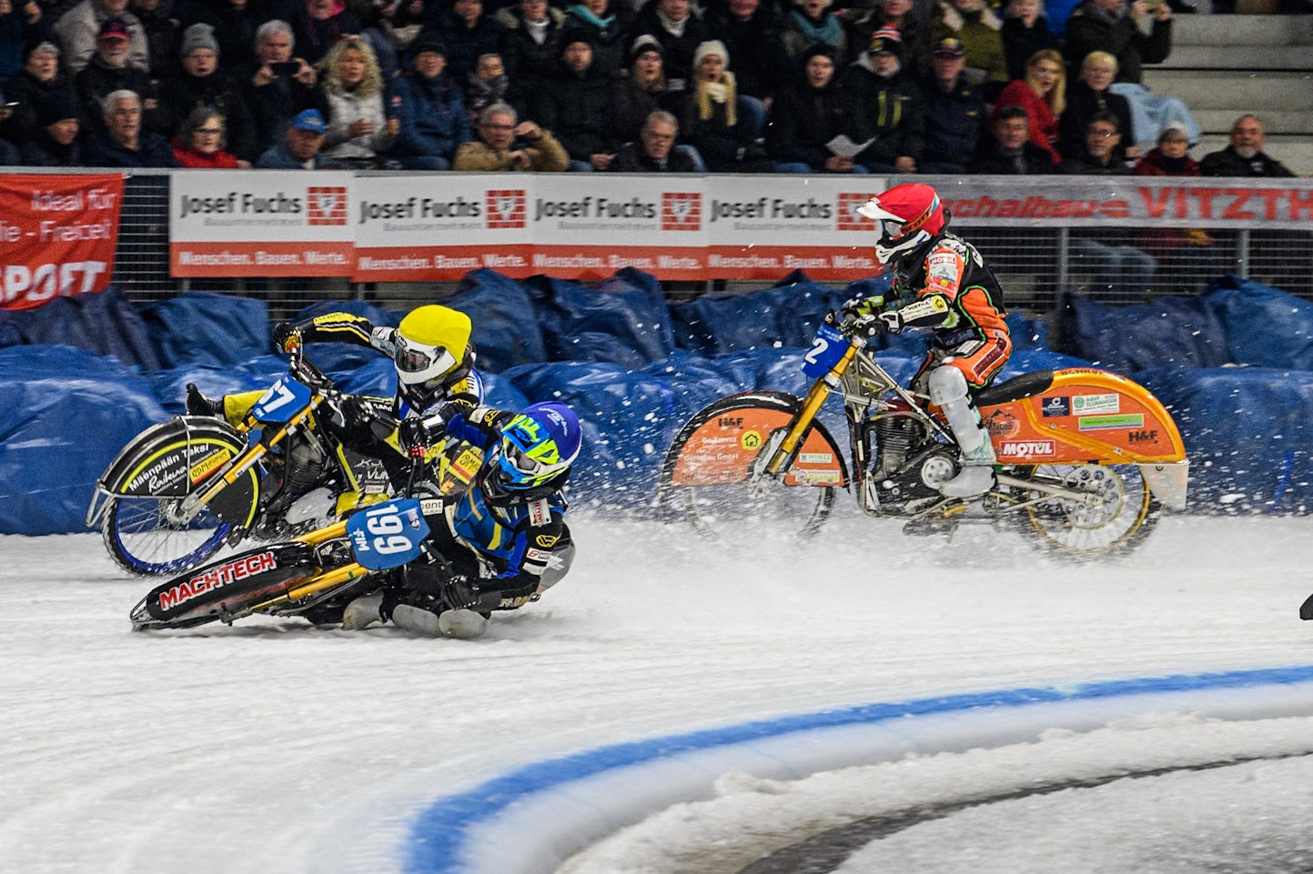 Sweden's Martin Haarahiltunen (199)  (Blue) leads  and Germany's Markus Jell (82) (Red) and Finland's Heikki Huusko (67)y\ collide and crash into the bales during the FIM Ice Speedway Gladiators World Championship Final 2 at the Max-Aicher-Arena, Inzell on Sunday 24 March 2024. (Photo: Ian Charles | MI News)