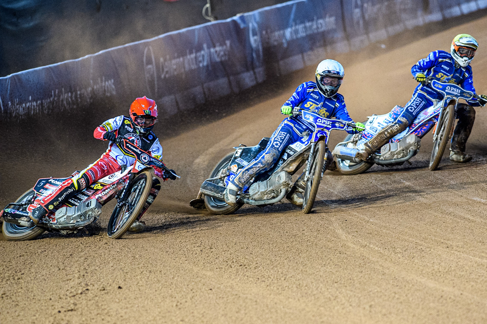 Dan Bewley of Belle Vue Aces in Red rides outside Nicolai Klindt of Kings Lynn Stars in White and Niels-Kristian Iversen of Kings Lynn Stars in Yellow during the Rowe Motor Oil Premiership match between Belle Vue Aces and King's Lynn Stars at the National Speedway Stadium, Manchester on Monday 5th April 2025. (Photo: Ian Charles | MI News)