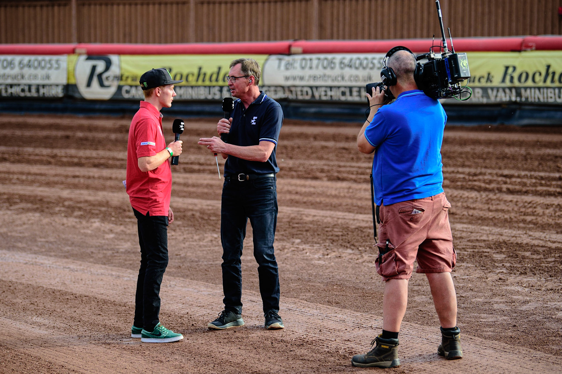 MANCHESTER UK  Eurosport cameras film commentator Kelvin Tatum  (centre) chatting with former Aces rider Dan Bewley about the track conditions during the SGB Premiership match between Belle Vue Aces and King's Lynn Stars at the National Speedway Stadium, Manchester on Monday 11th July 2022. (Credit: Ian Charles | MI News)